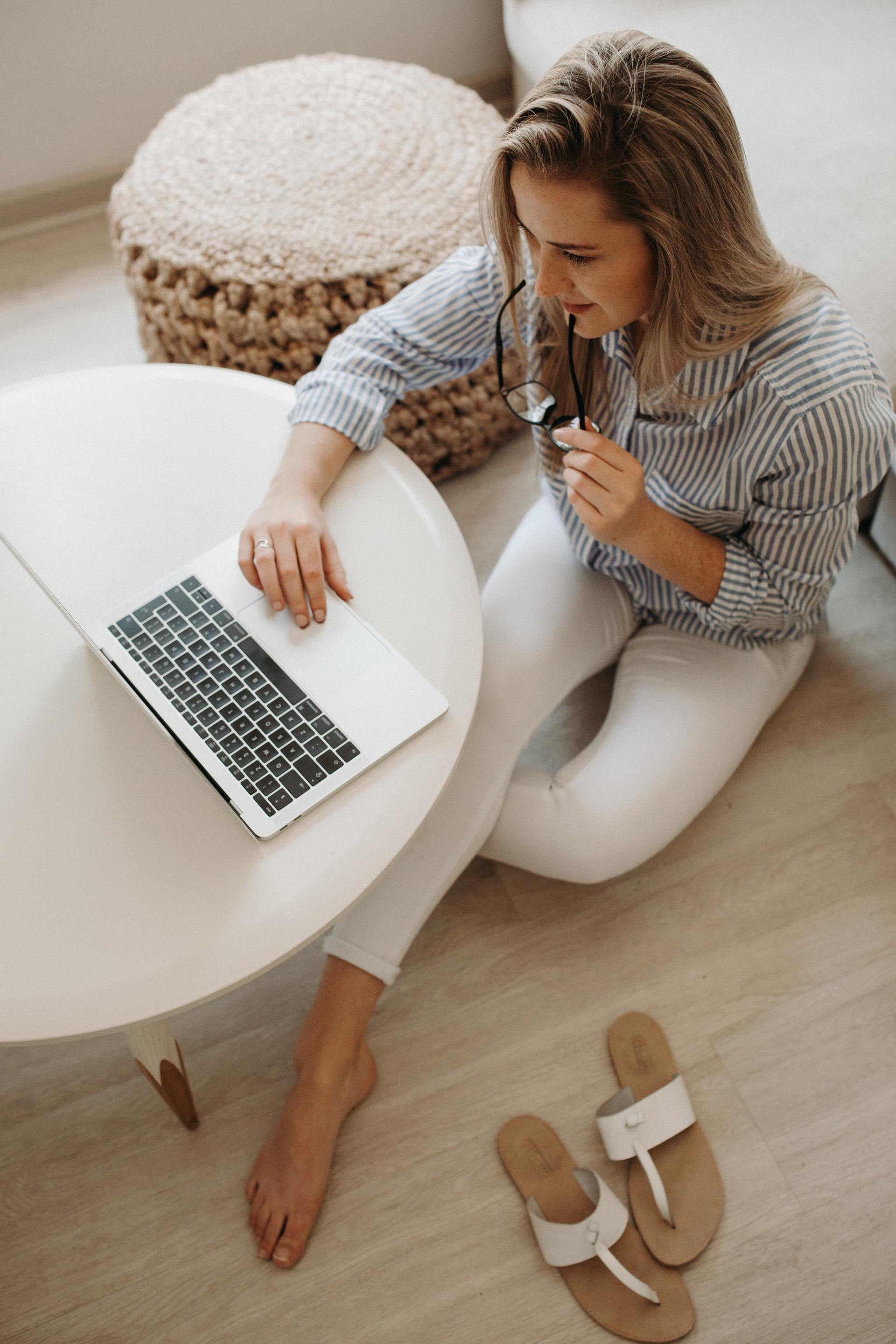 A woman is sitting on the floor using a laptop computer.