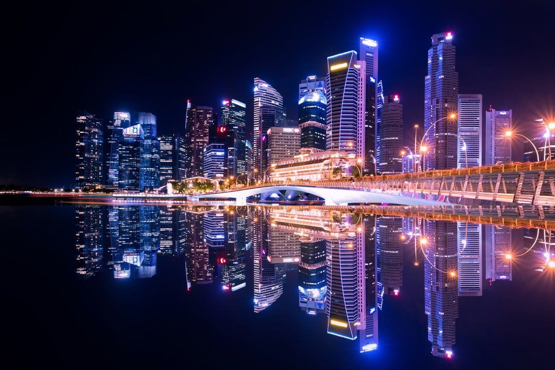 a city skyline is reflected in the water at night