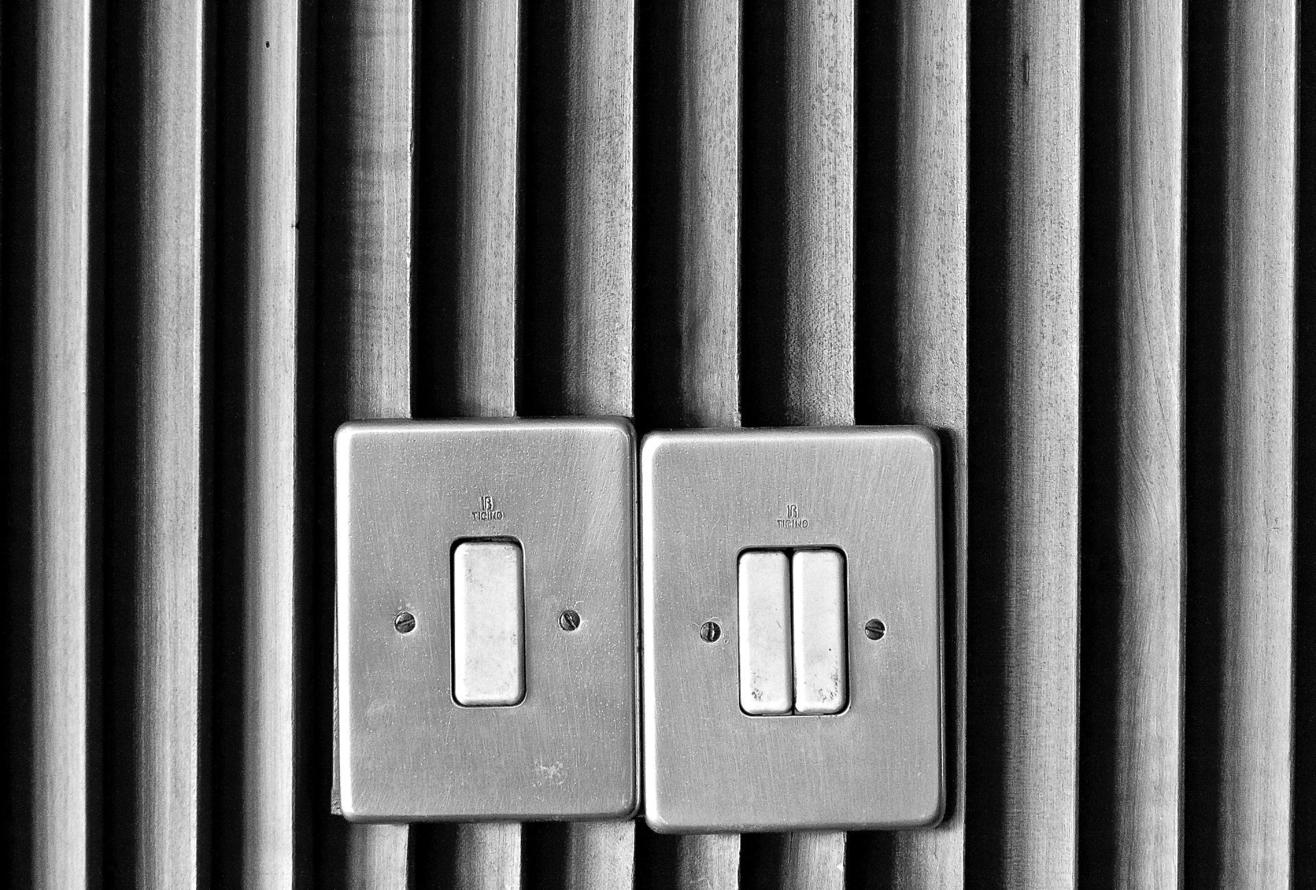 A black and white photo of two light switches on a wall.