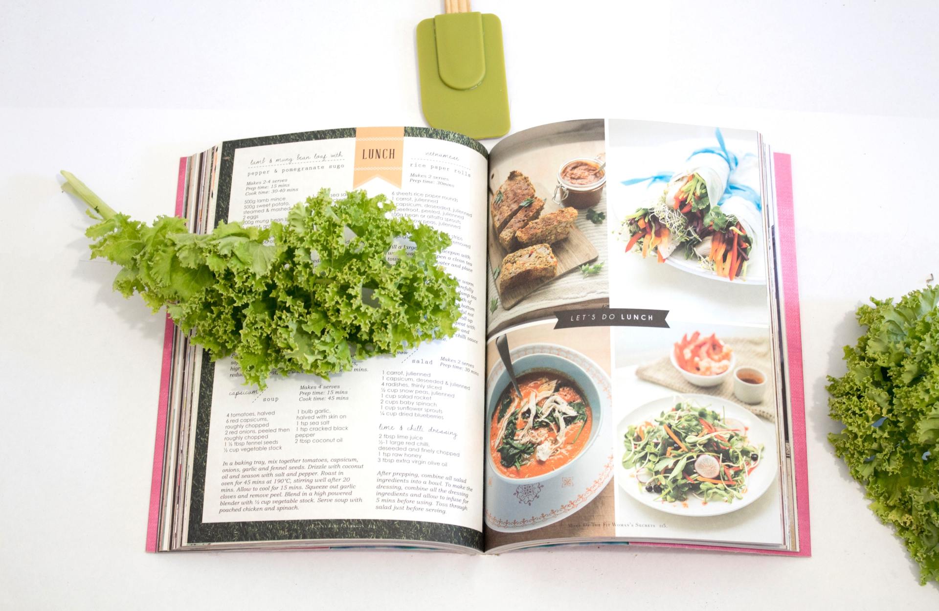 A cookbook is open to a page with a bunch of lettuce on it.