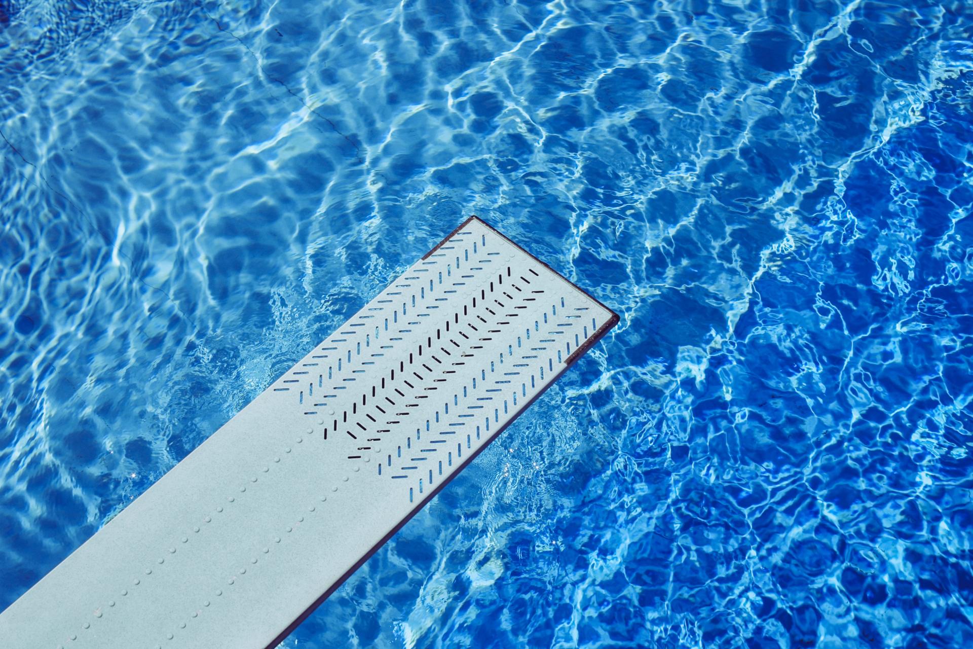 A diving board is in the middle of a swimming pool.