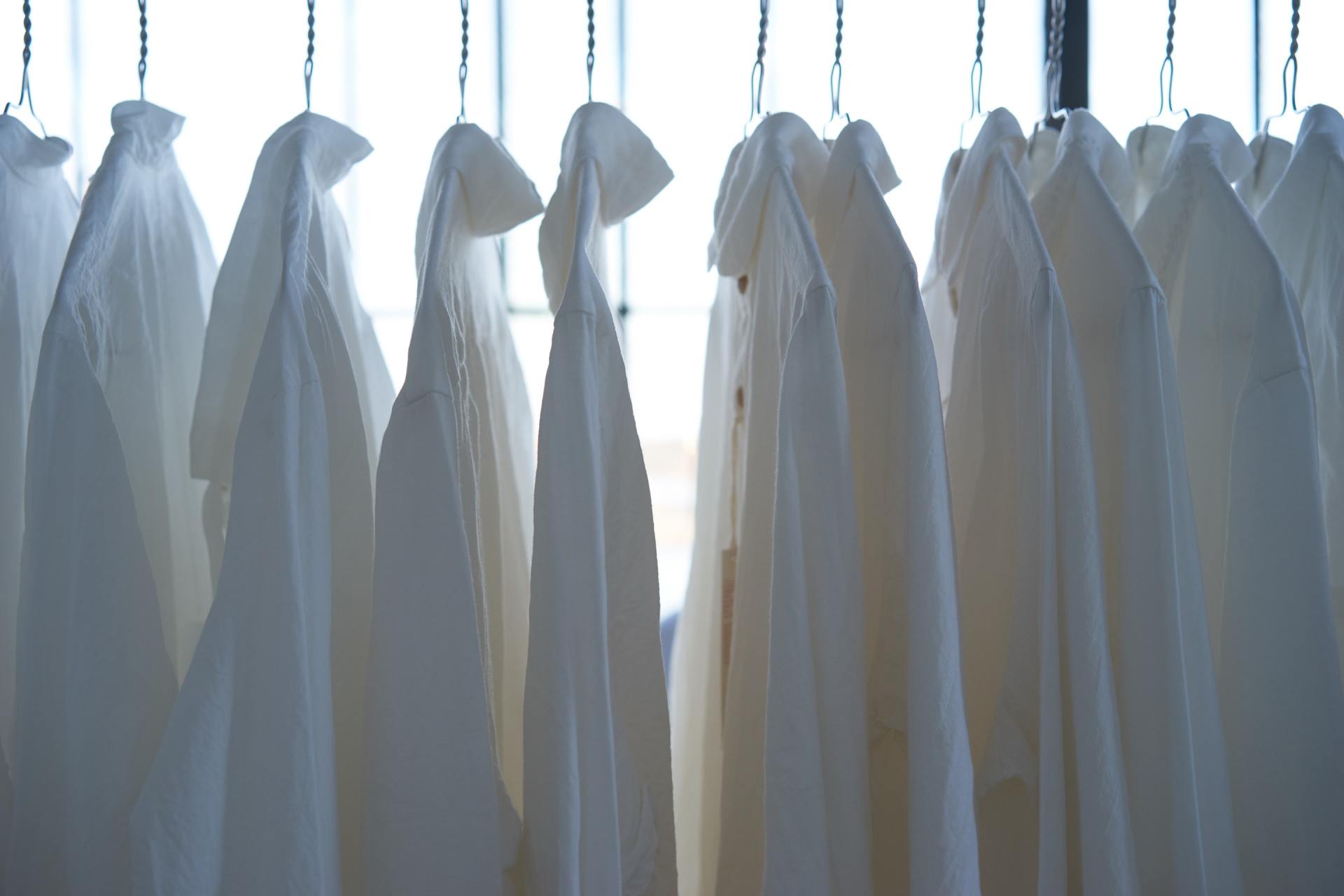 White shirts hanging on a rail in front of a window