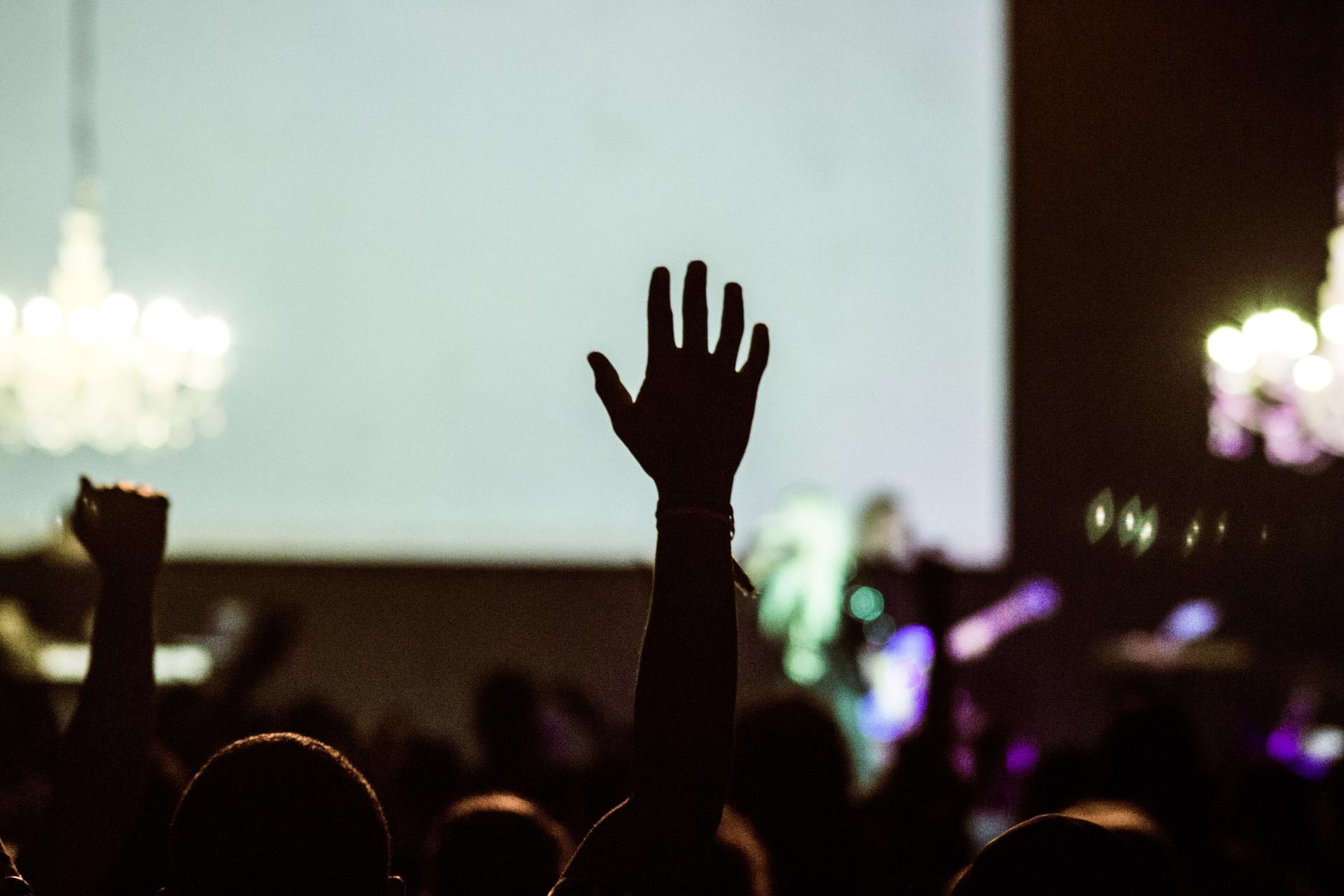 A crowd of people are raising their hands in the air at a concert.