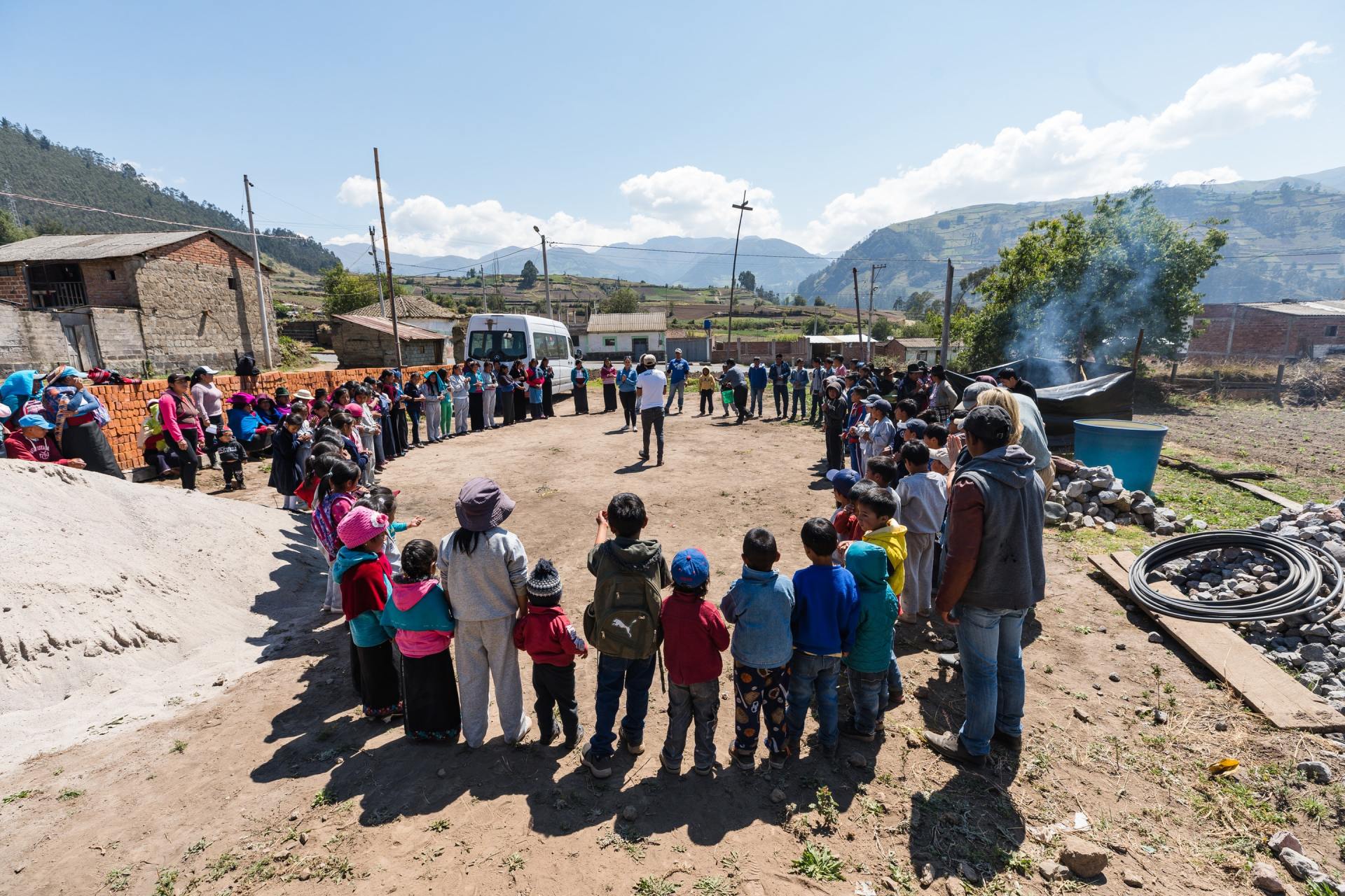 A group of people are standing in a circle in a dirt field.