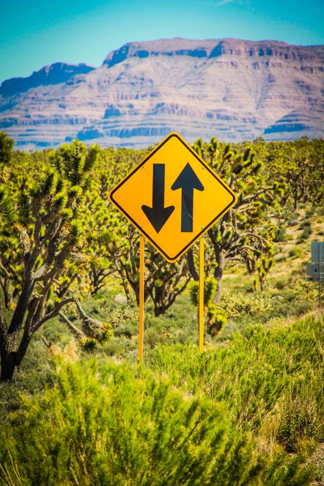 road sign showing up and down against backdrop of mountains