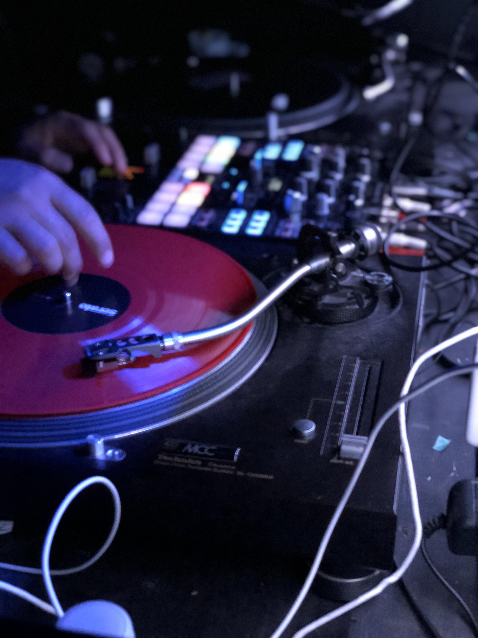 A dj is playing a red record on a turntable