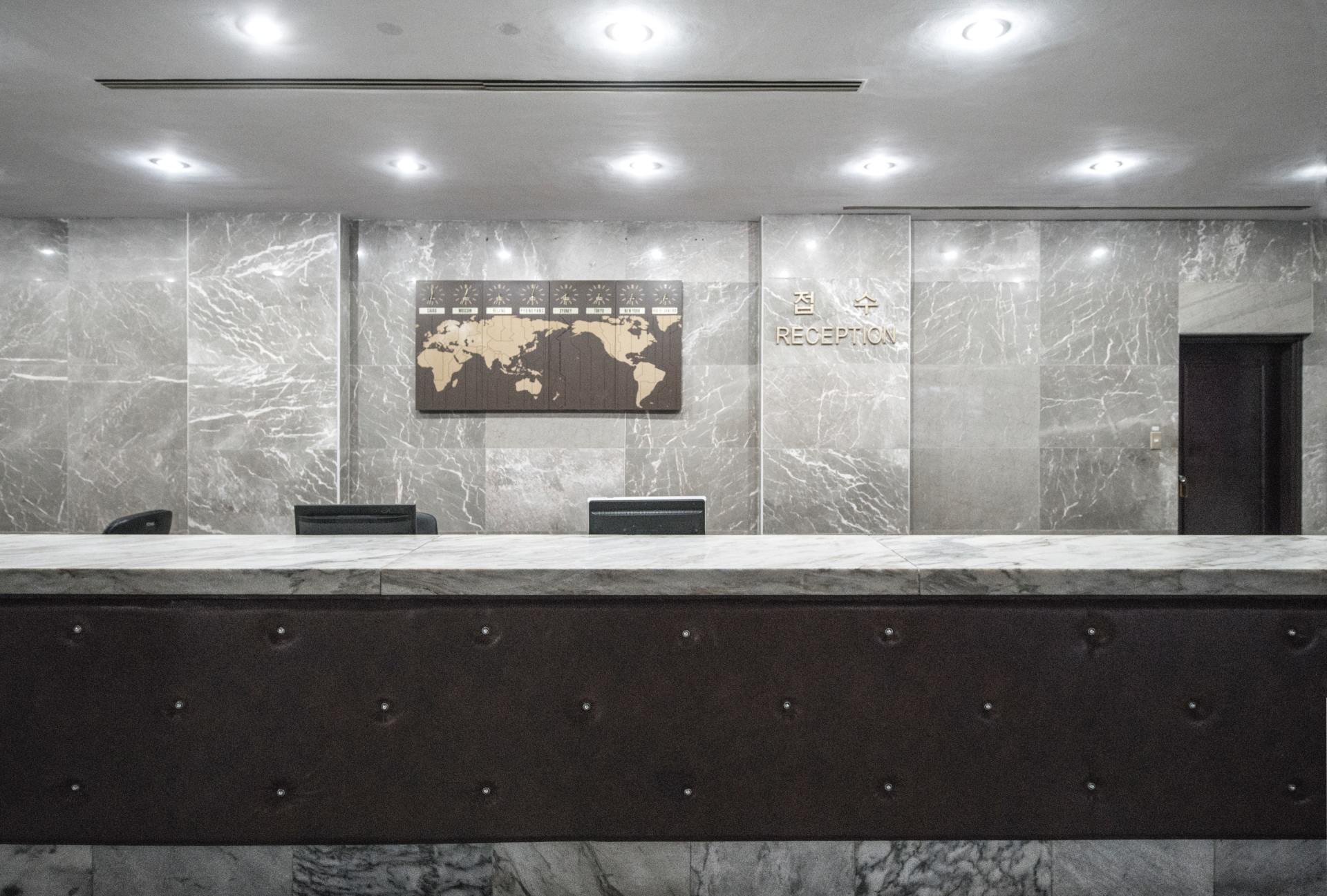 A hotel lobby with a map of the world on the wall above the reception desk.