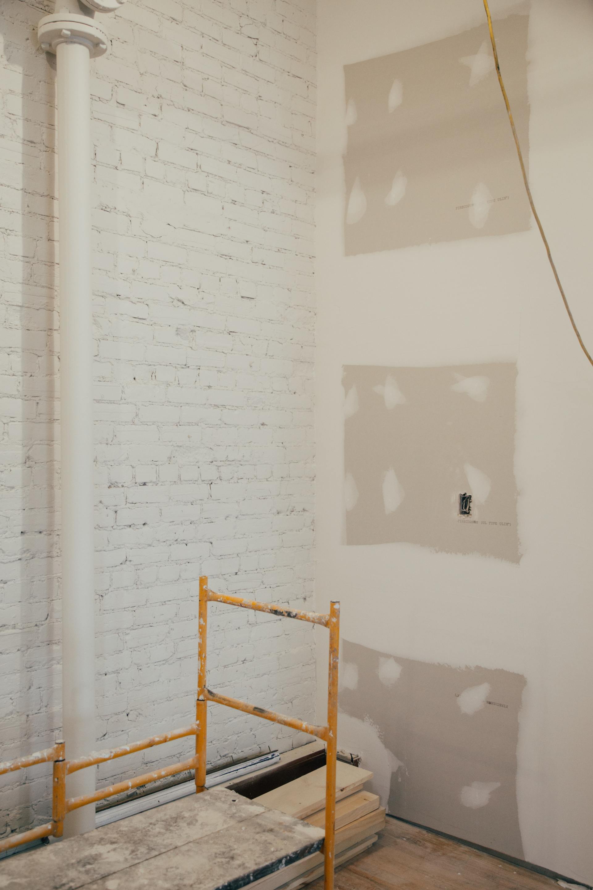 A room with white brick walls and a scaffolding in the corner.