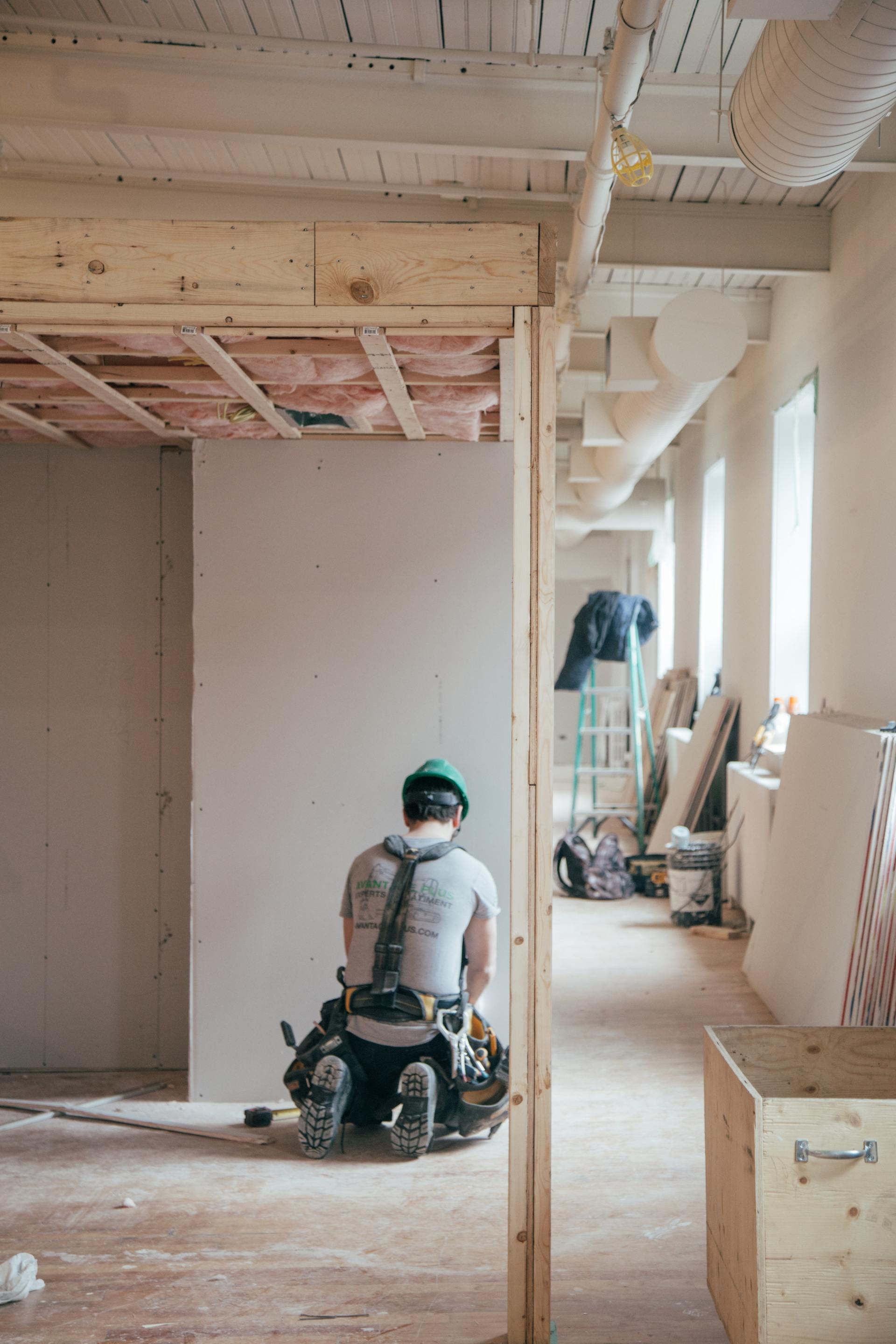 a man is kneeling down in a room under construction .