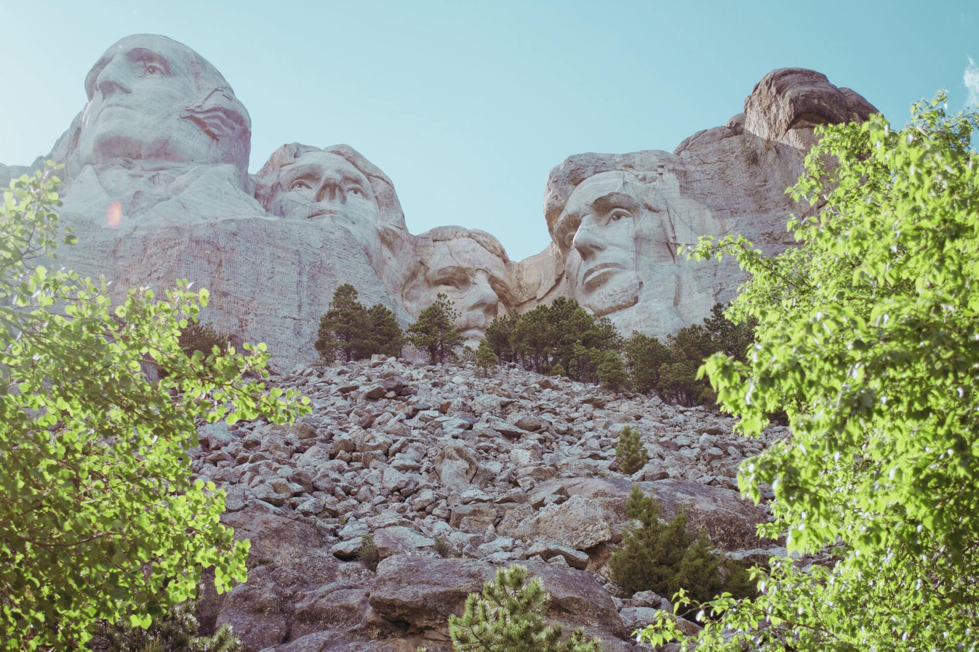 A group of statues on top of a rocky hill with trees in the foreground.
