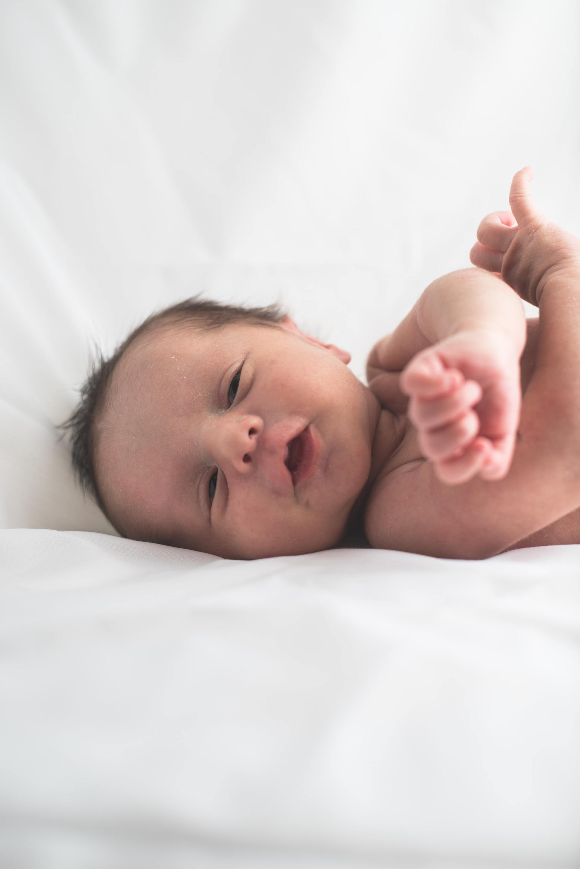 Beautiful baby on a white blanket, smiling at the camera