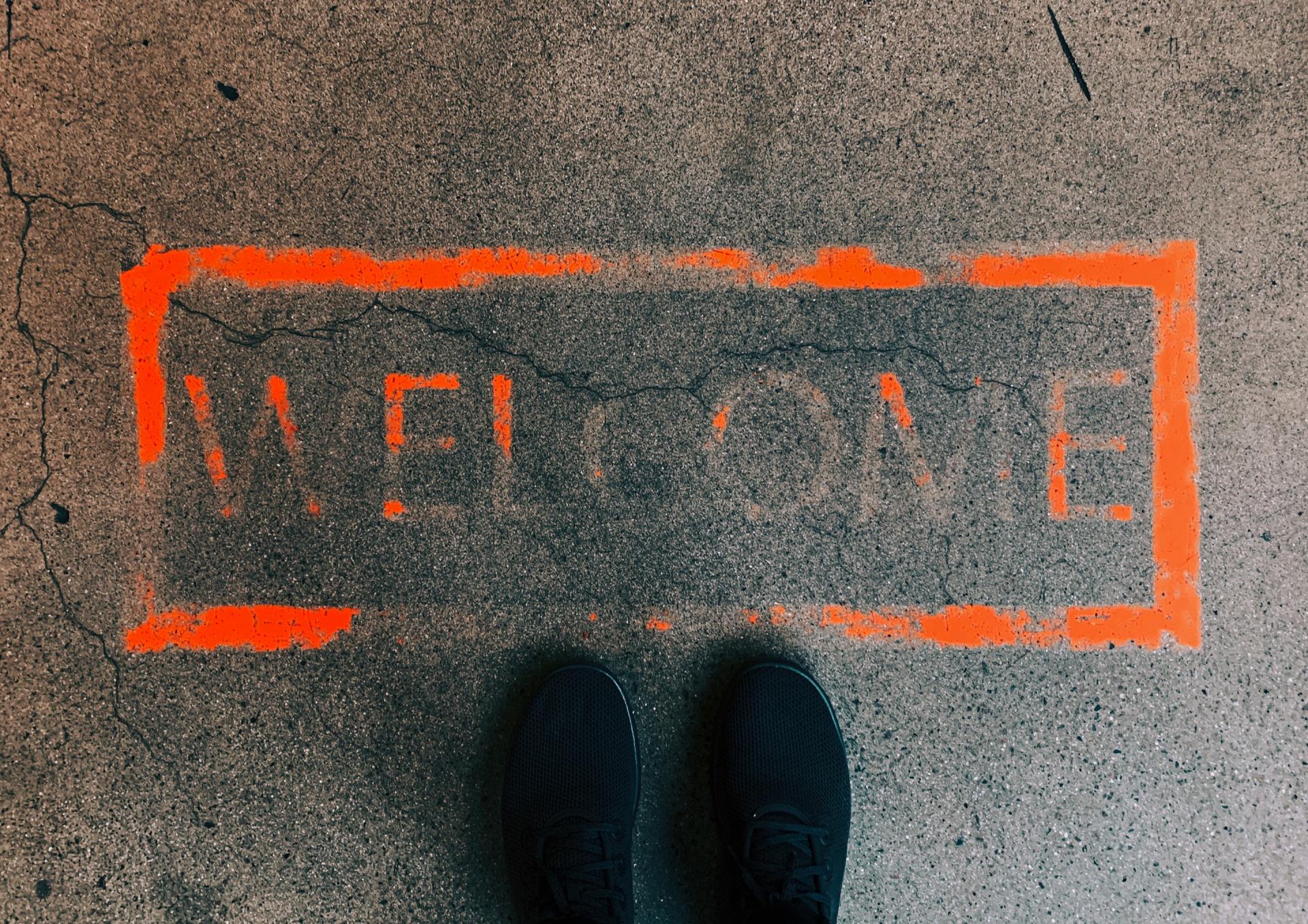 a person is standing in front of a welcome mat painted on the ground .