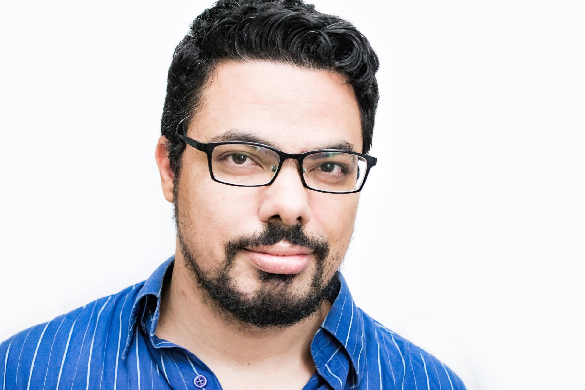 A man with a beard wearing glasses and a blue shirt