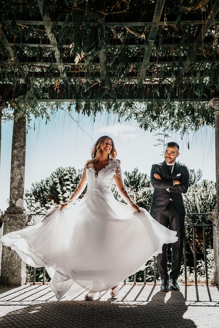 A bride and groom are posing for a picture under a pergola.