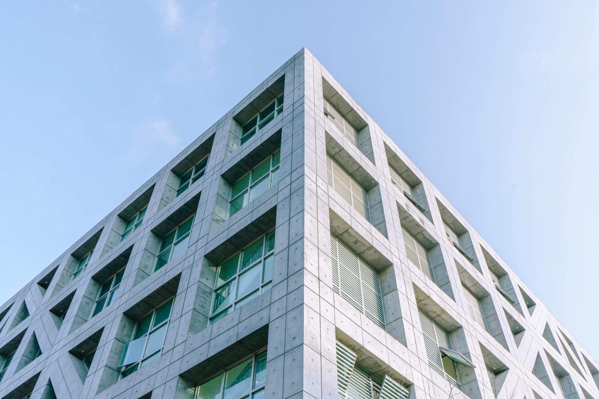 Looking up at the corner of a tall building with a blue sky in the background.