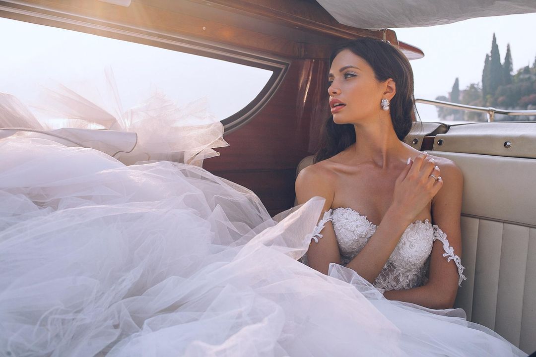 Sposa in un auto con un vestito da sposa voluminoso