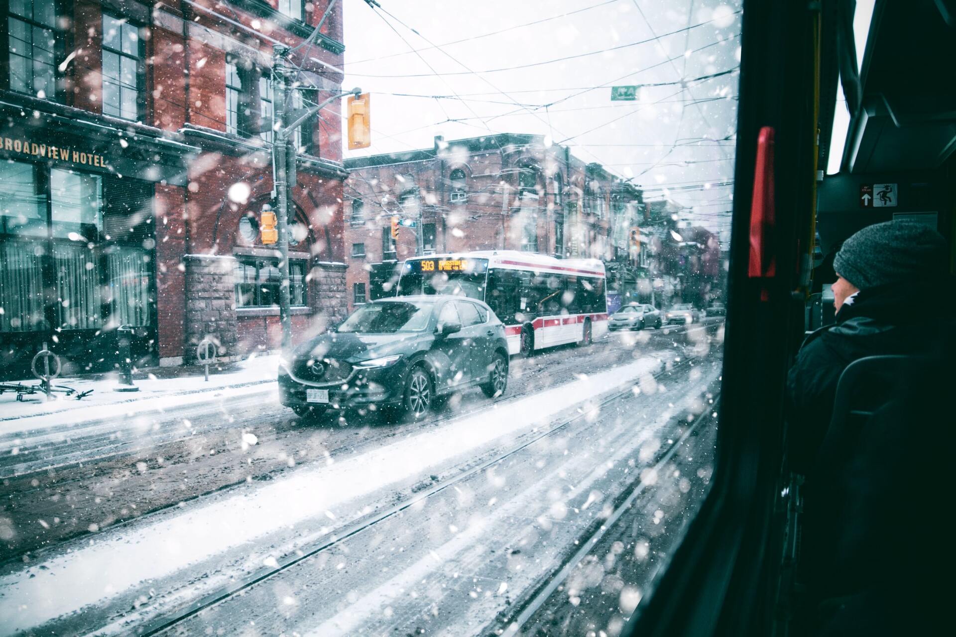 A bus is driving down a snowy street in a city.