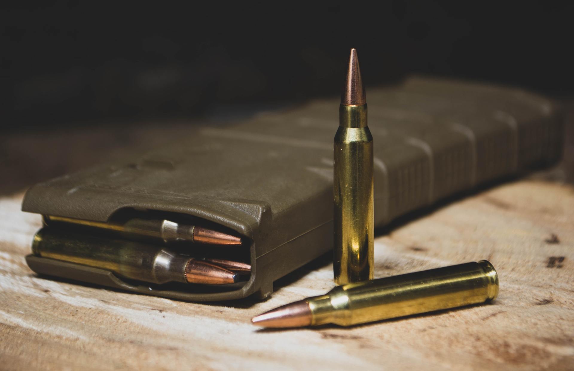 A magazine filled with bullets is sitting on a wooden table.