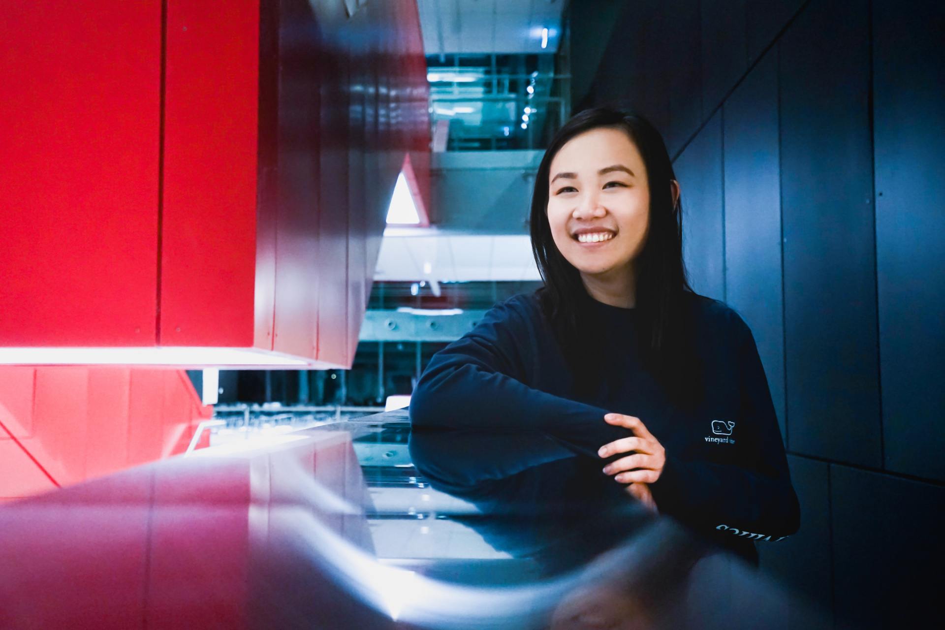 A woman is leaning against a wall and smiling.