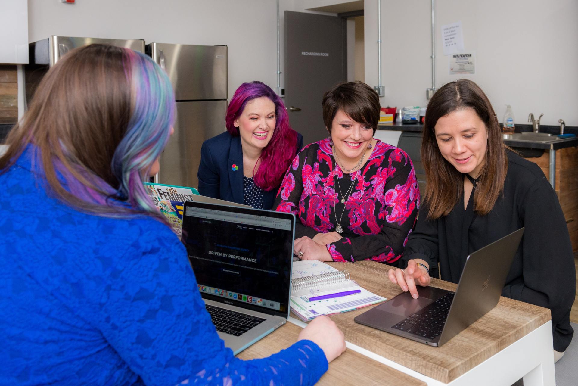 A group of women are sitting at a table with laptops.