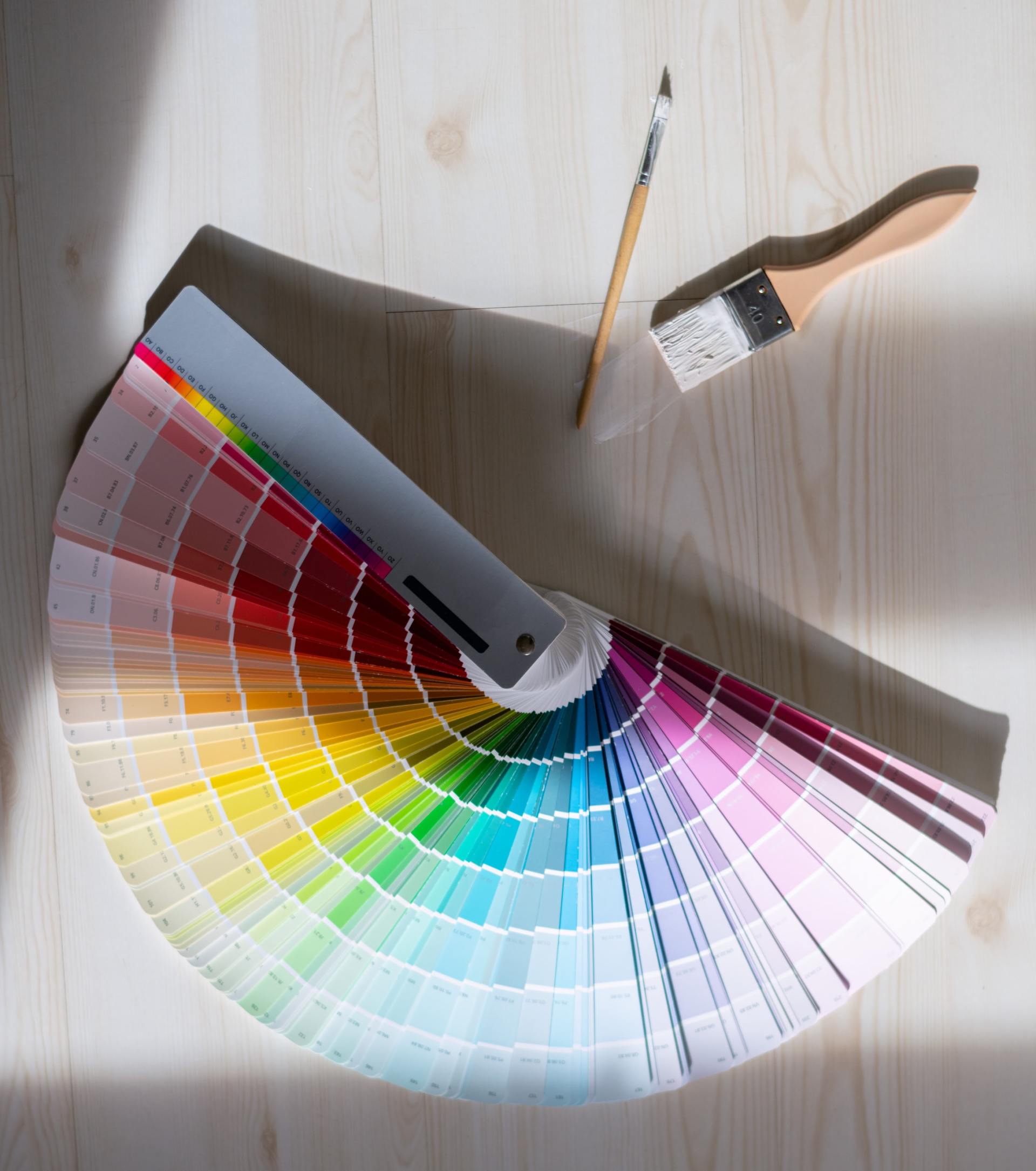 A fan of paint samples and a paint brush on a table