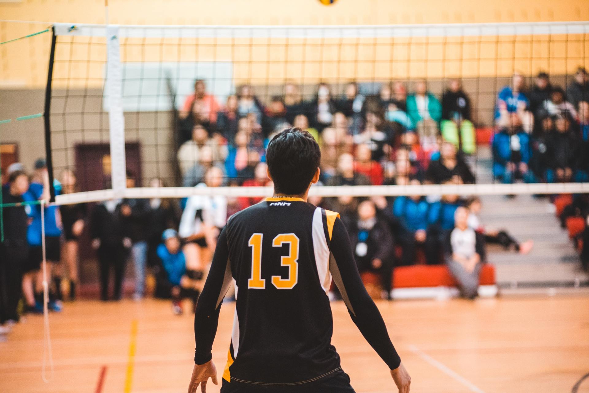 A man is playing volleyball on a court in front of a crowd.