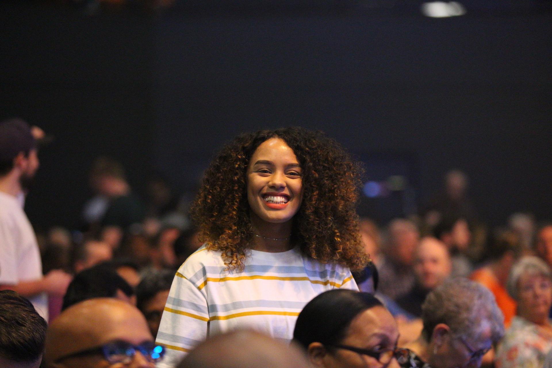 smiling young woman in crowd at conference