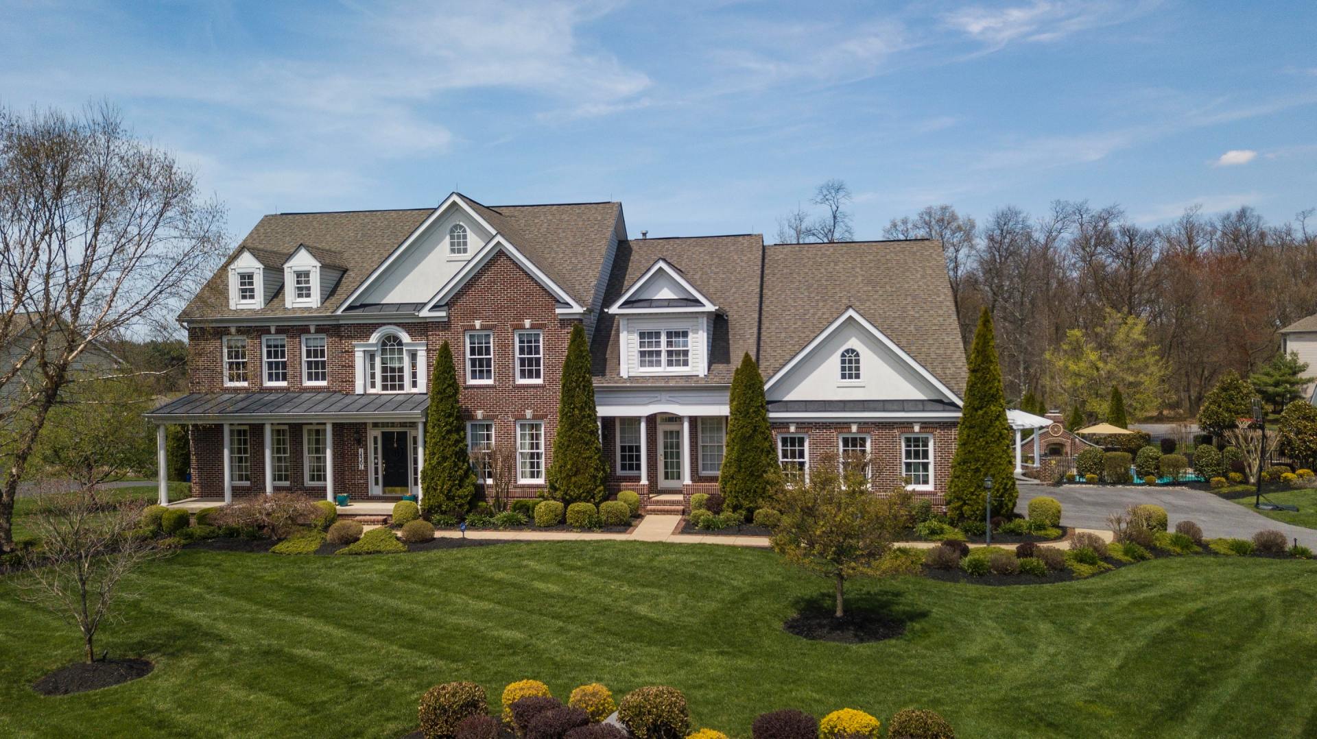 An aerial view of a large brick house with a large lawn in front of it.
