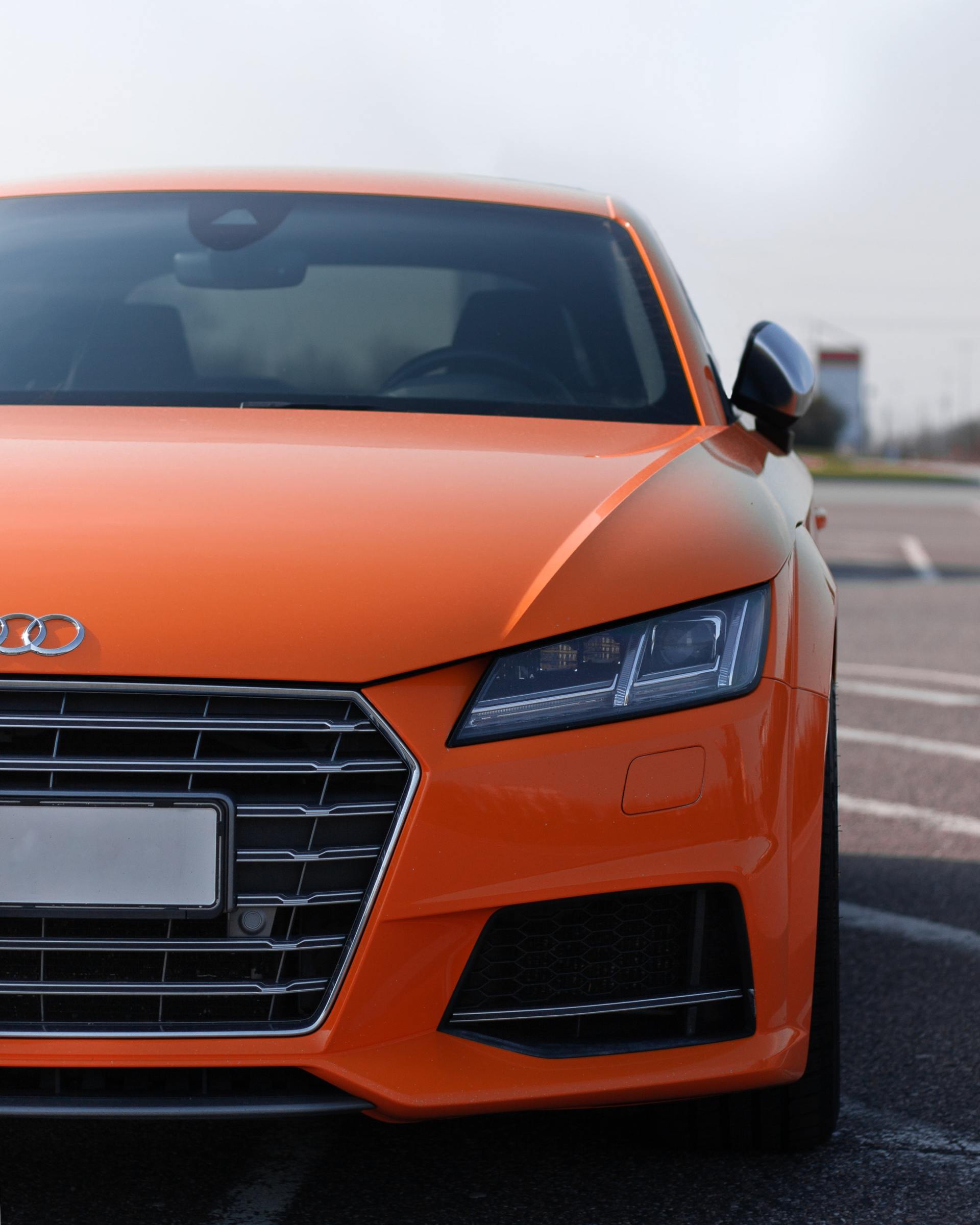 An orange audi car is parked in a parking lot