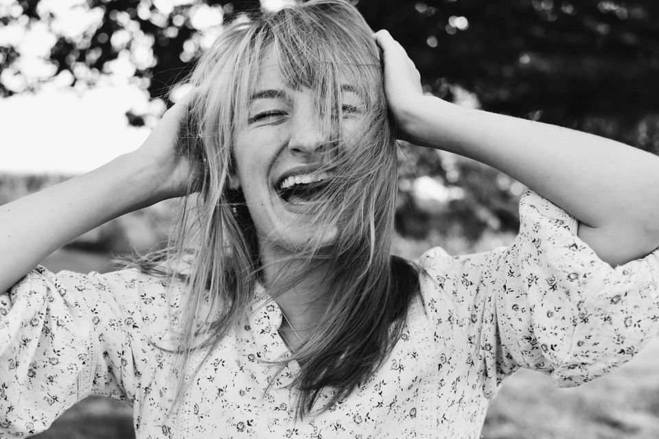 woman holding head laughing