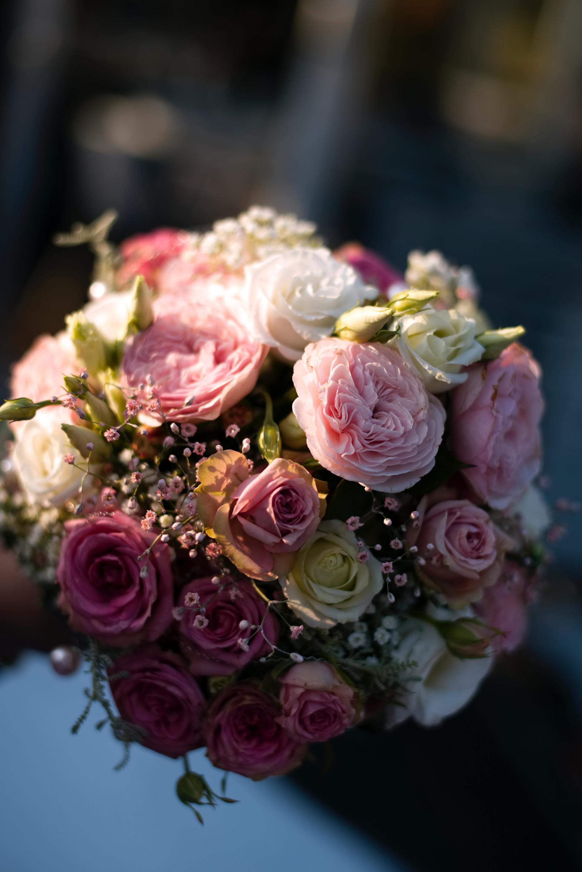 Eine Person hält einen Strauß rosa und weißer Rosen in der Hand.