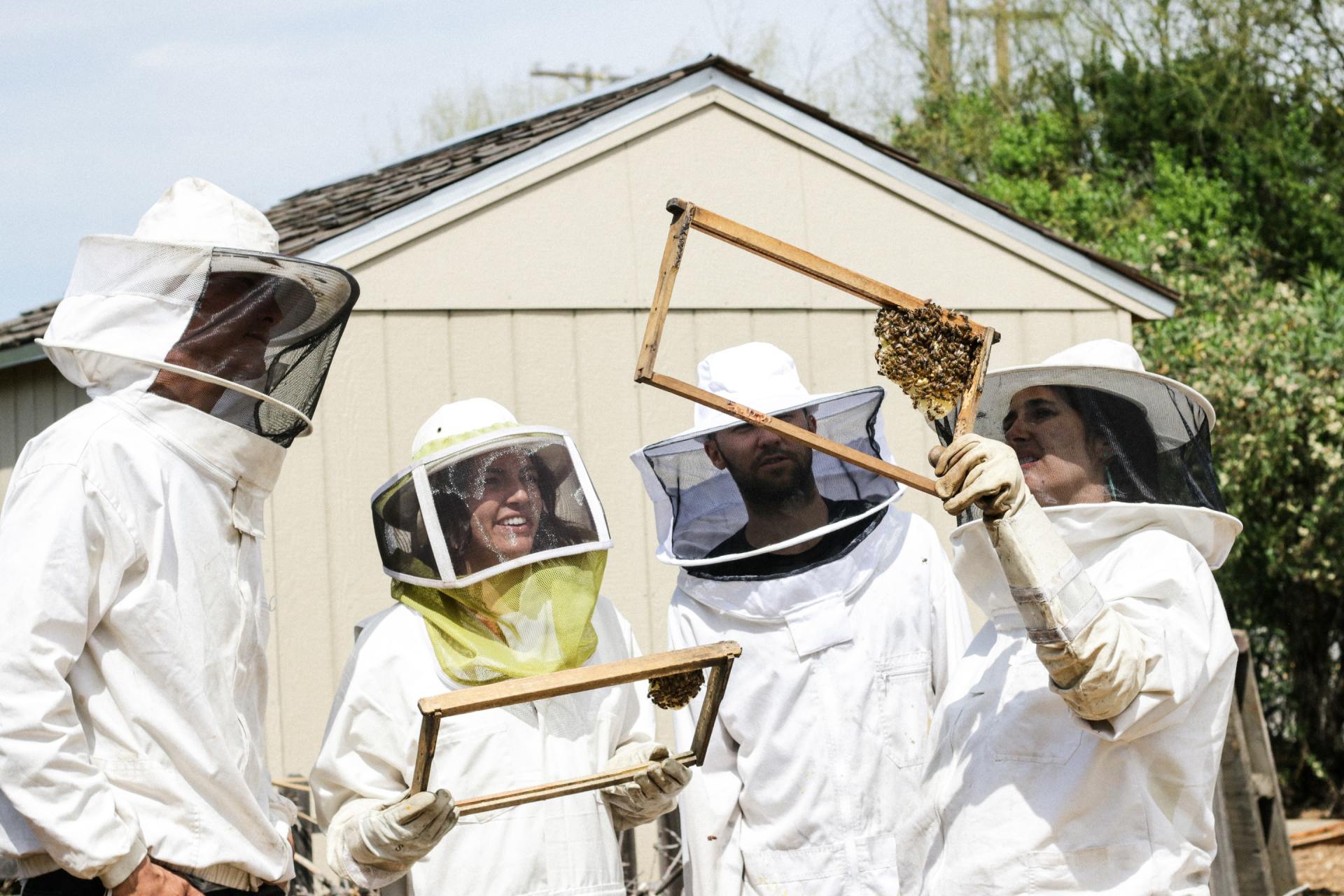 A group of Colorado beekeepers are standing in front of a shed holding frames.