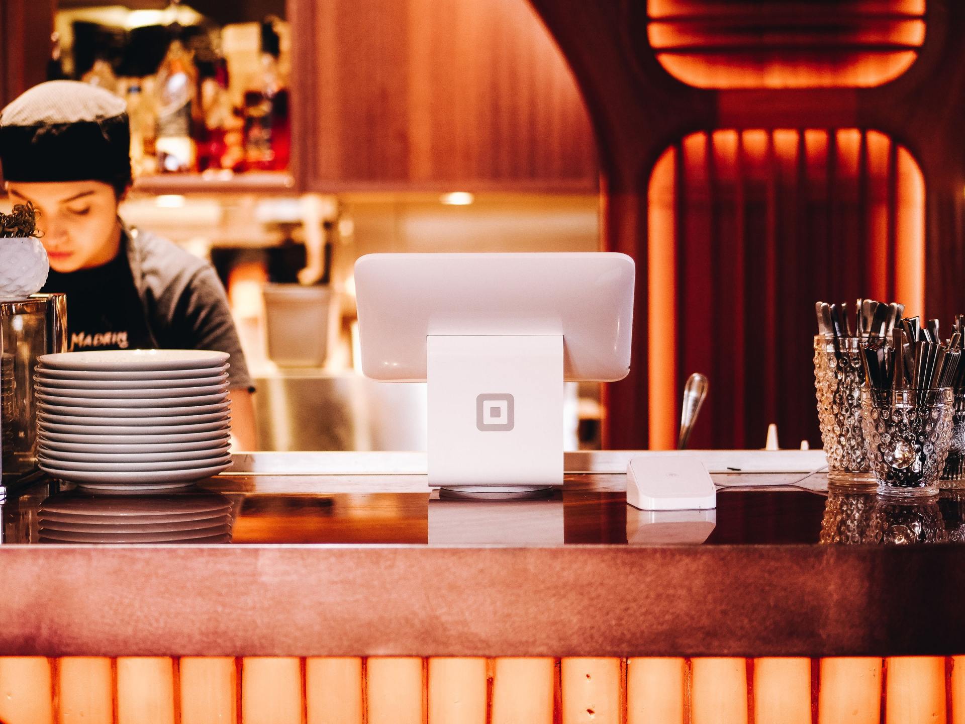 A man in a chef 's hat is behind a counter in a restaurant.