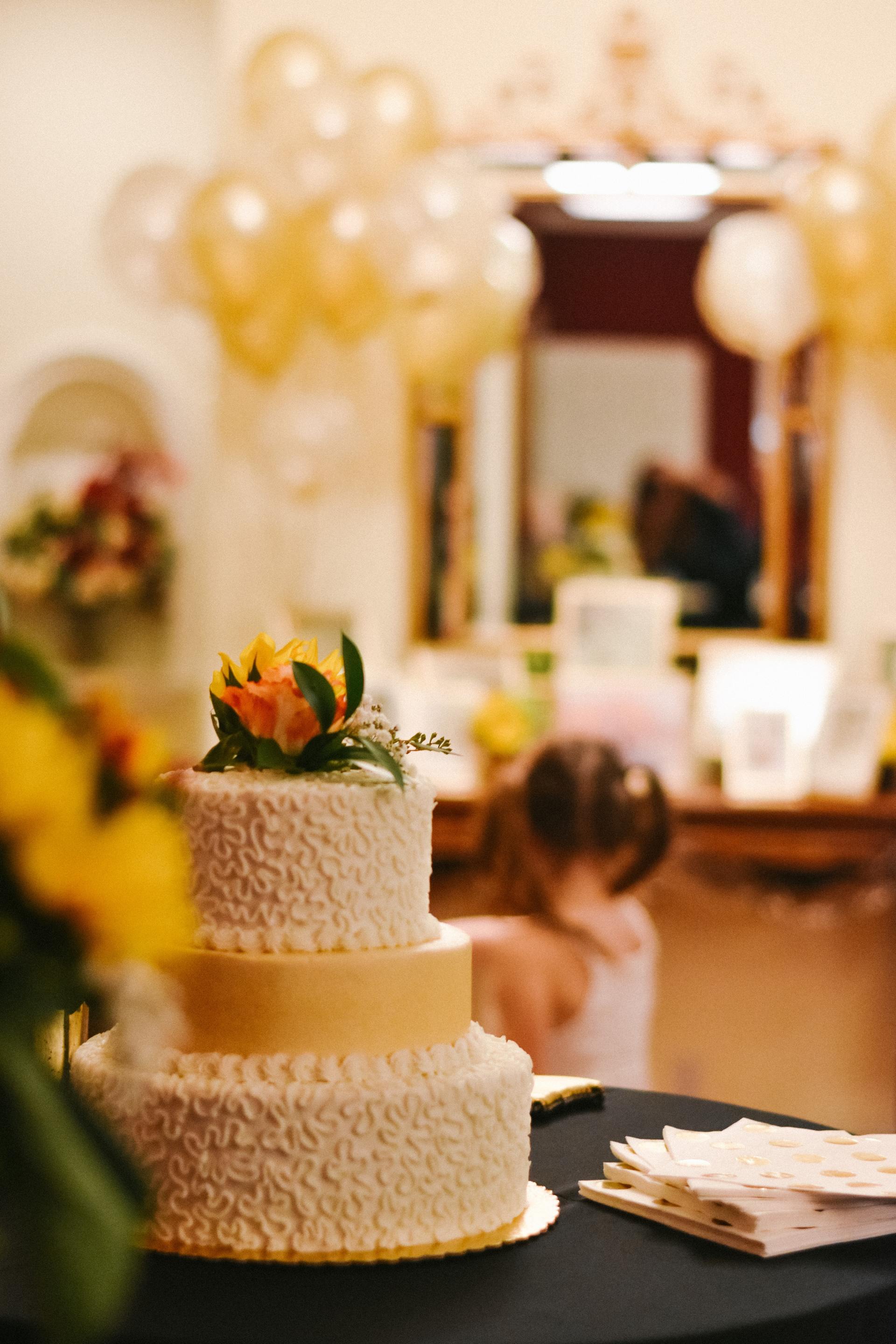 a three tiered cake with flowers on top sits on a table