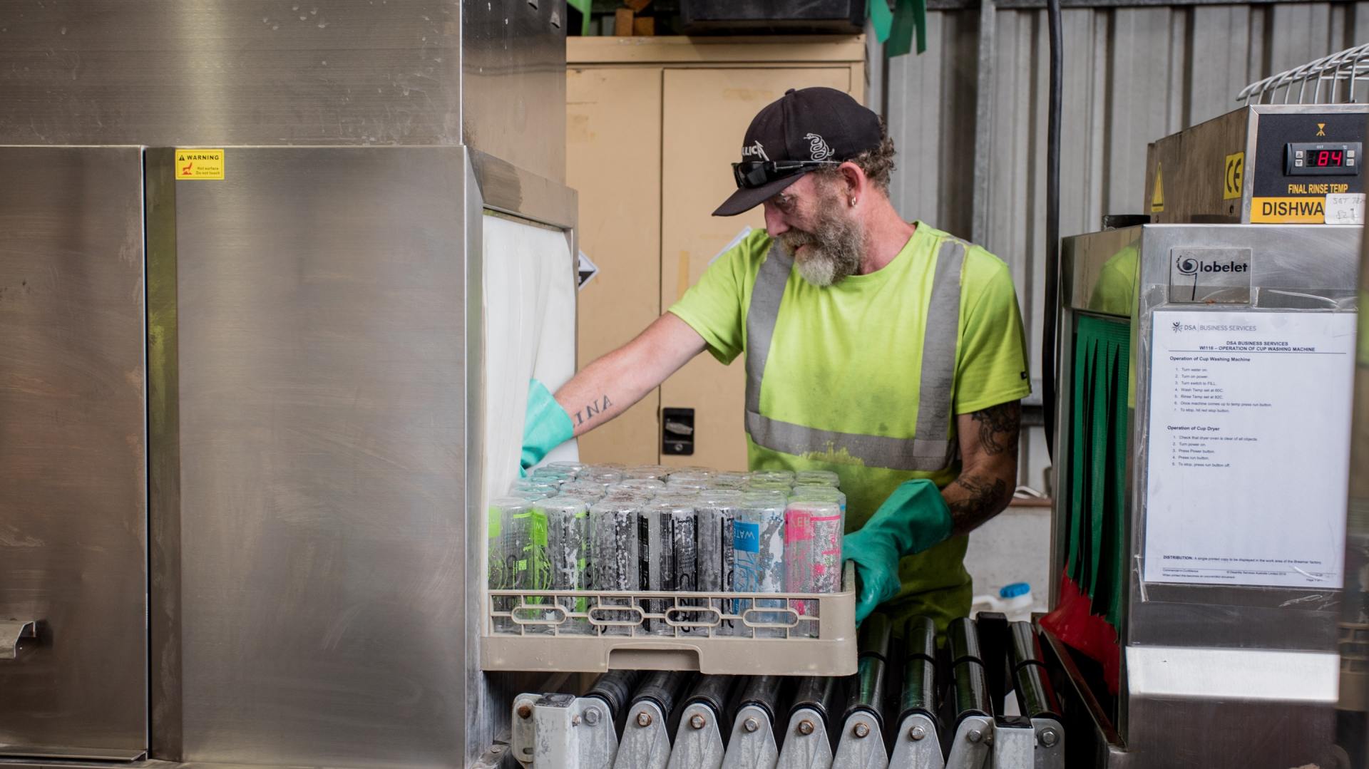 A man is loading bottles into a dishwasher in a kitchen.