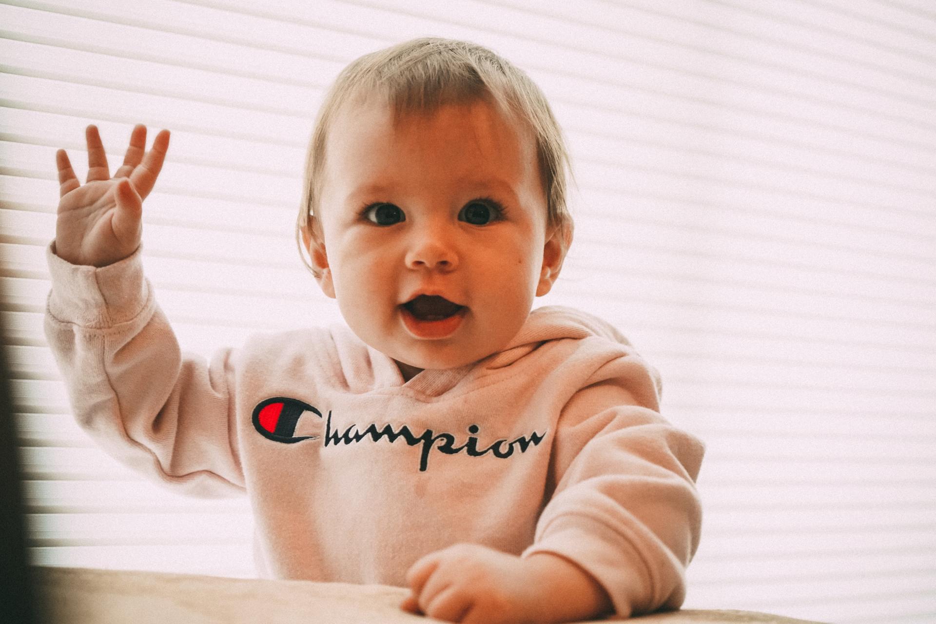 Grinning toddler waving at the camera