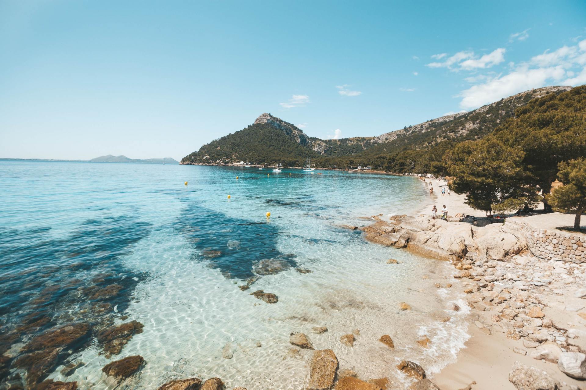 Ein Strand mit einem Berg im Hintergrund und einer großen Wasserfläche.