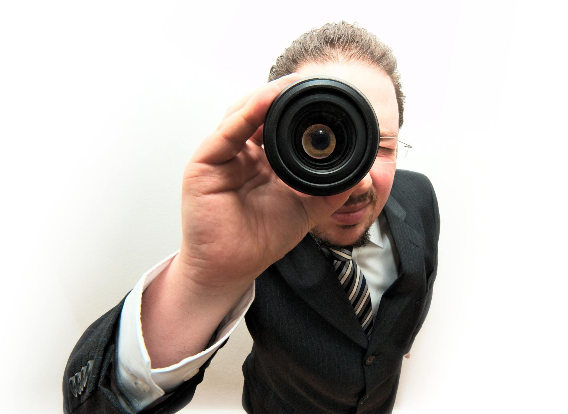 a man in a suit is looking through a camera lens