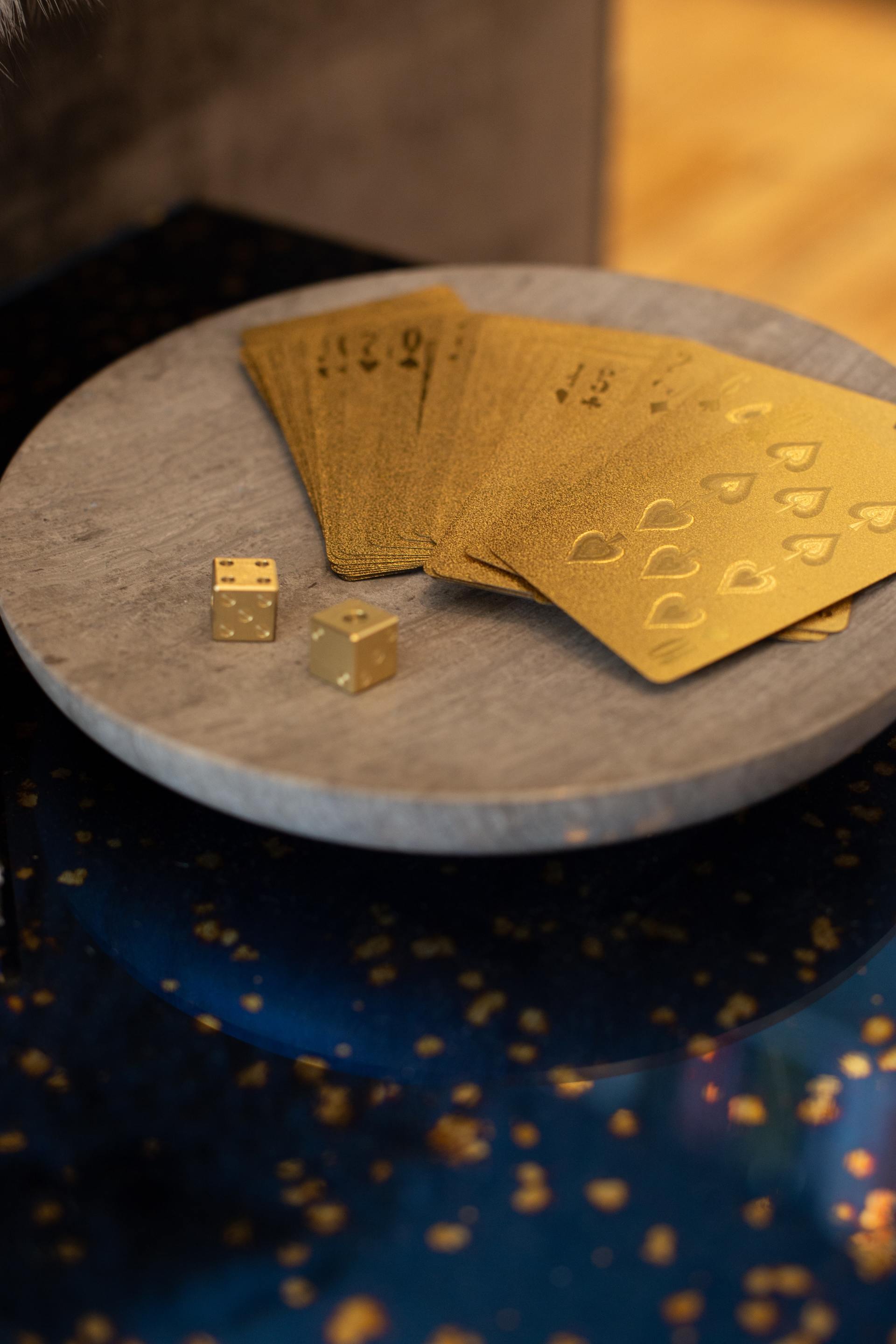 A marble plate topped with gold playing cards and dice.