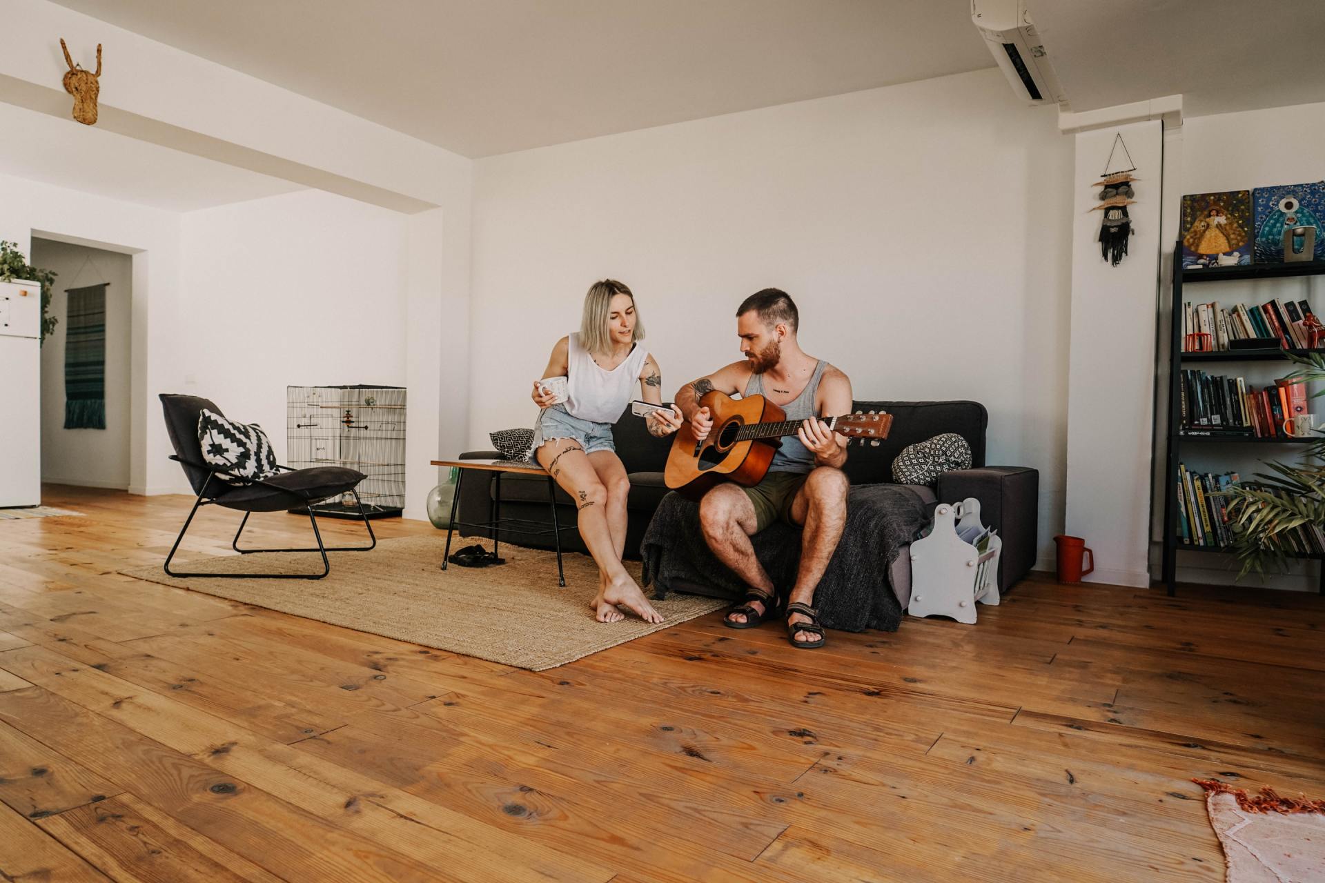 happy couple sitting on couch in living room with wood floors