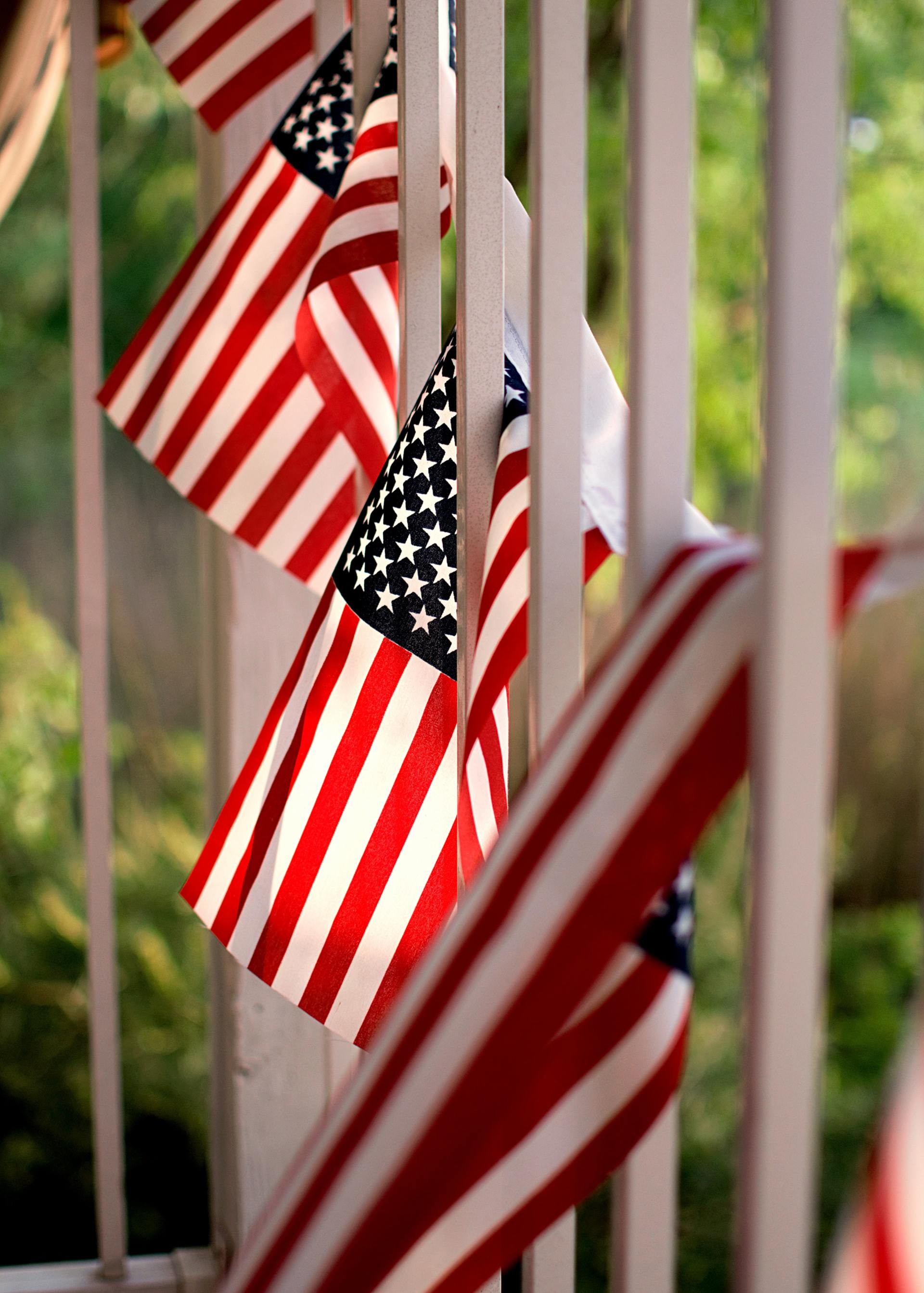 A bunch of american flags hanging from a railing