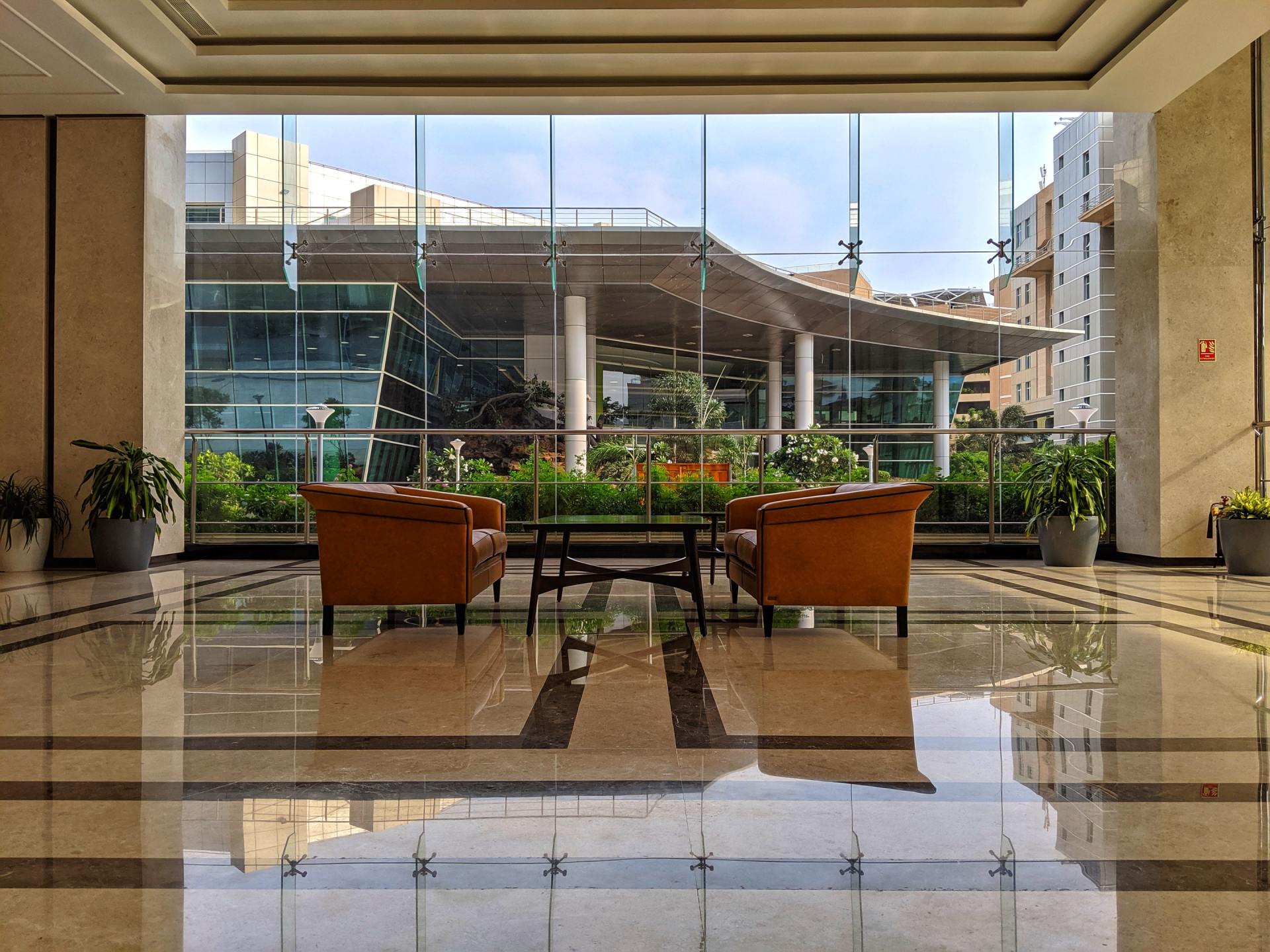 Two leather chairs face a table in front of a glass wall overlooking an outdoor patio.