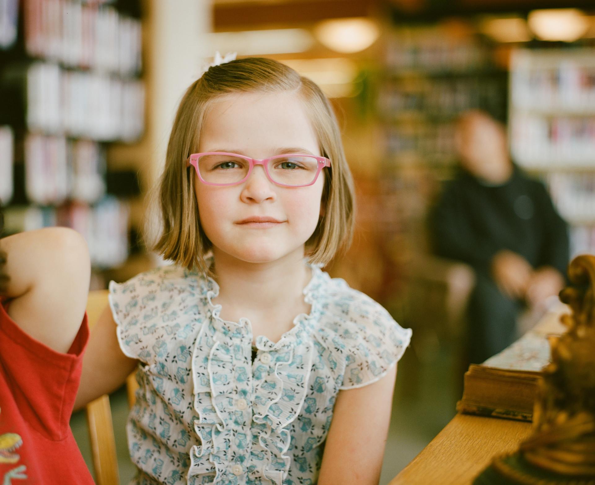 Little girl staring at camera weaking pink glasses