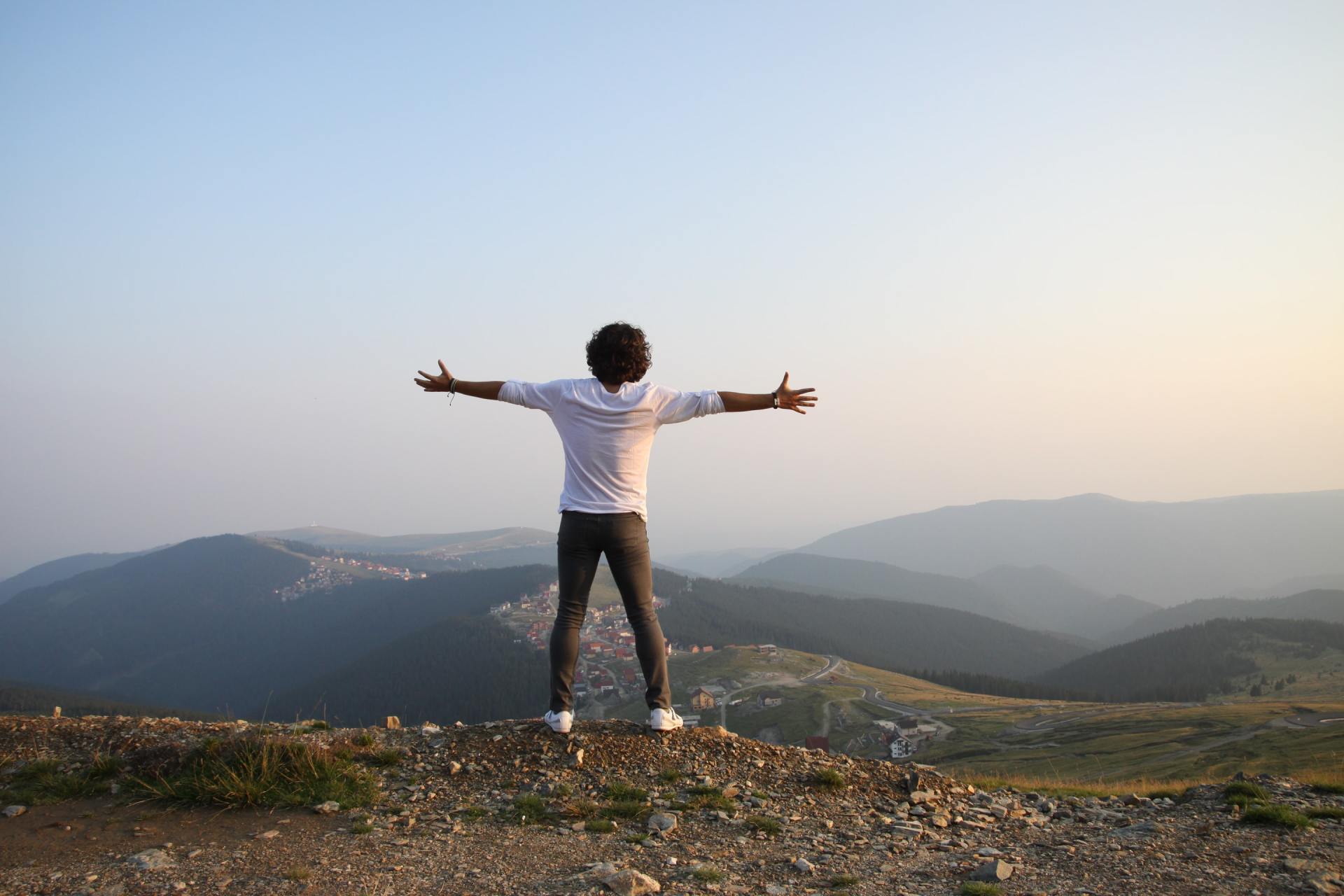 person standing atop mountains with outstretched arms