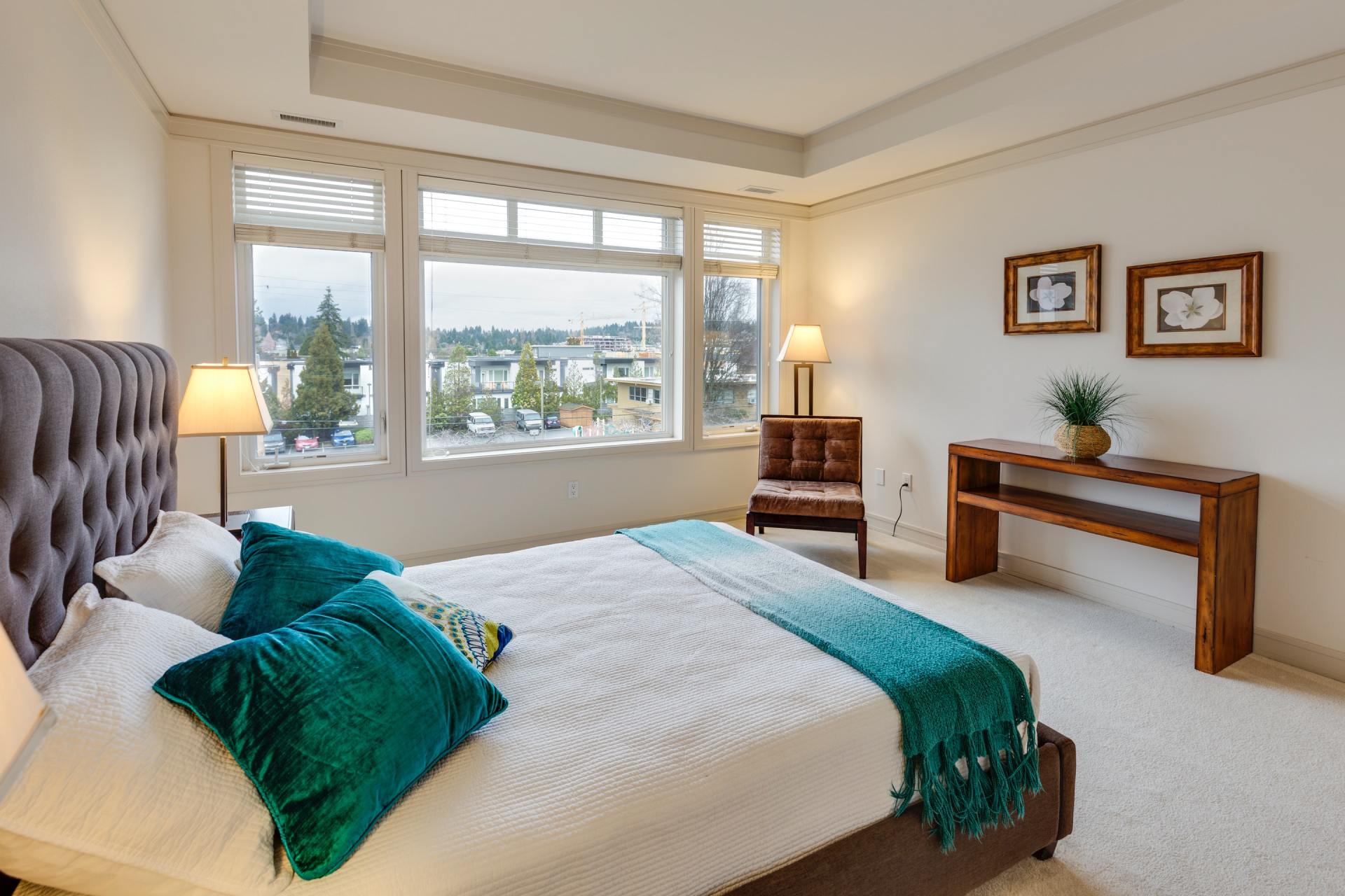 A bedroom with a bed , chair , table and windows.