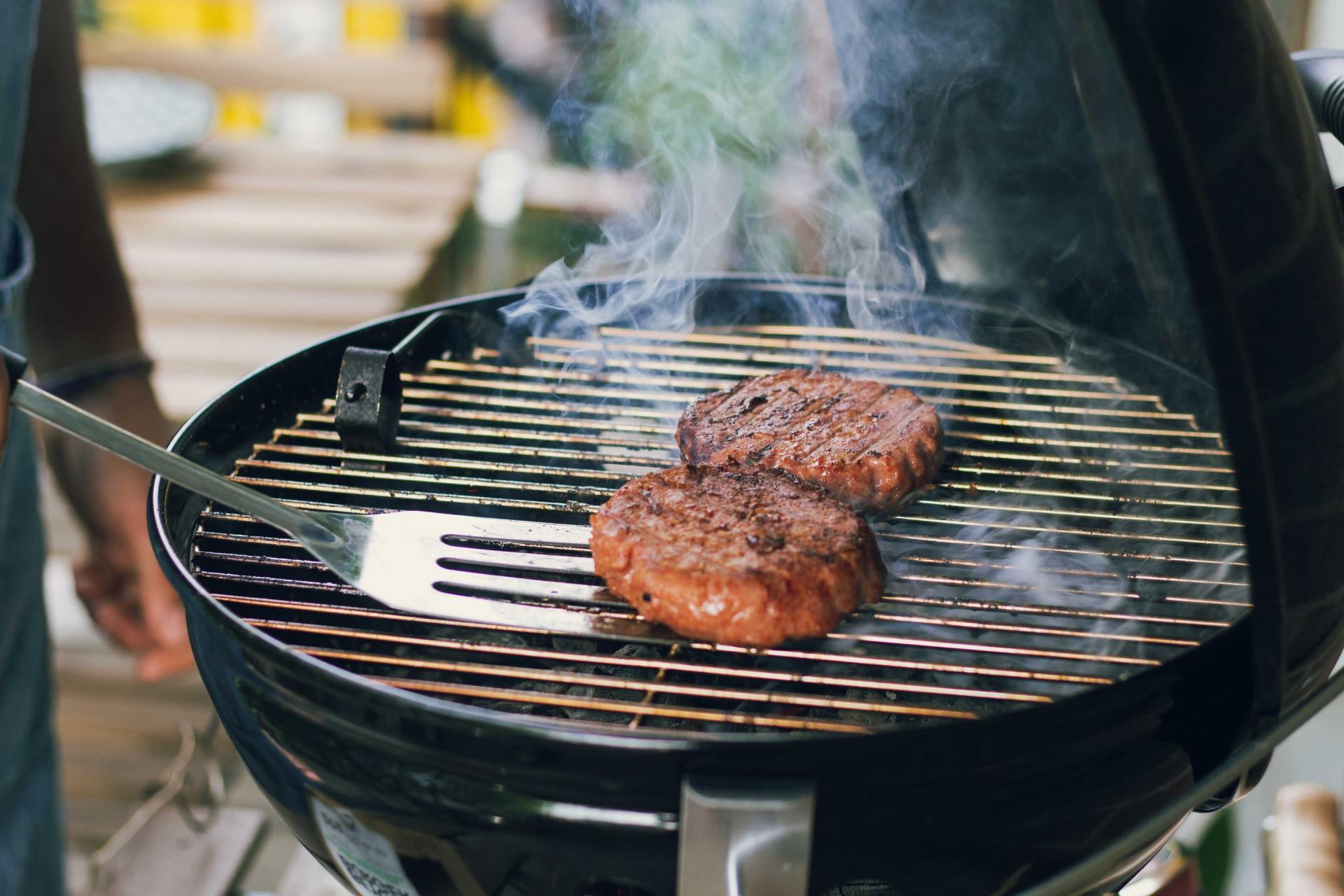 burgers cooking on the grill with smoke rising from grill