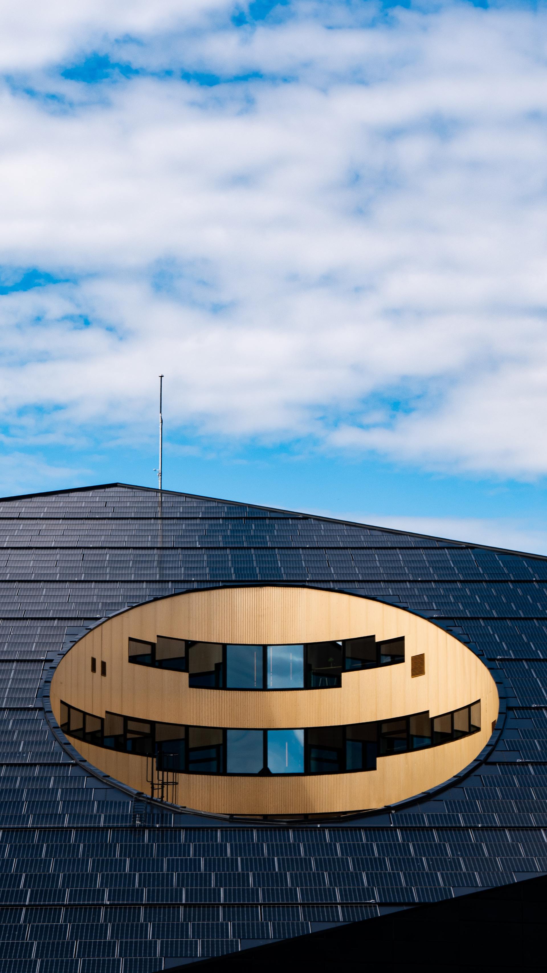 En stor oval byggnad med en blå himmel i bakgrunden