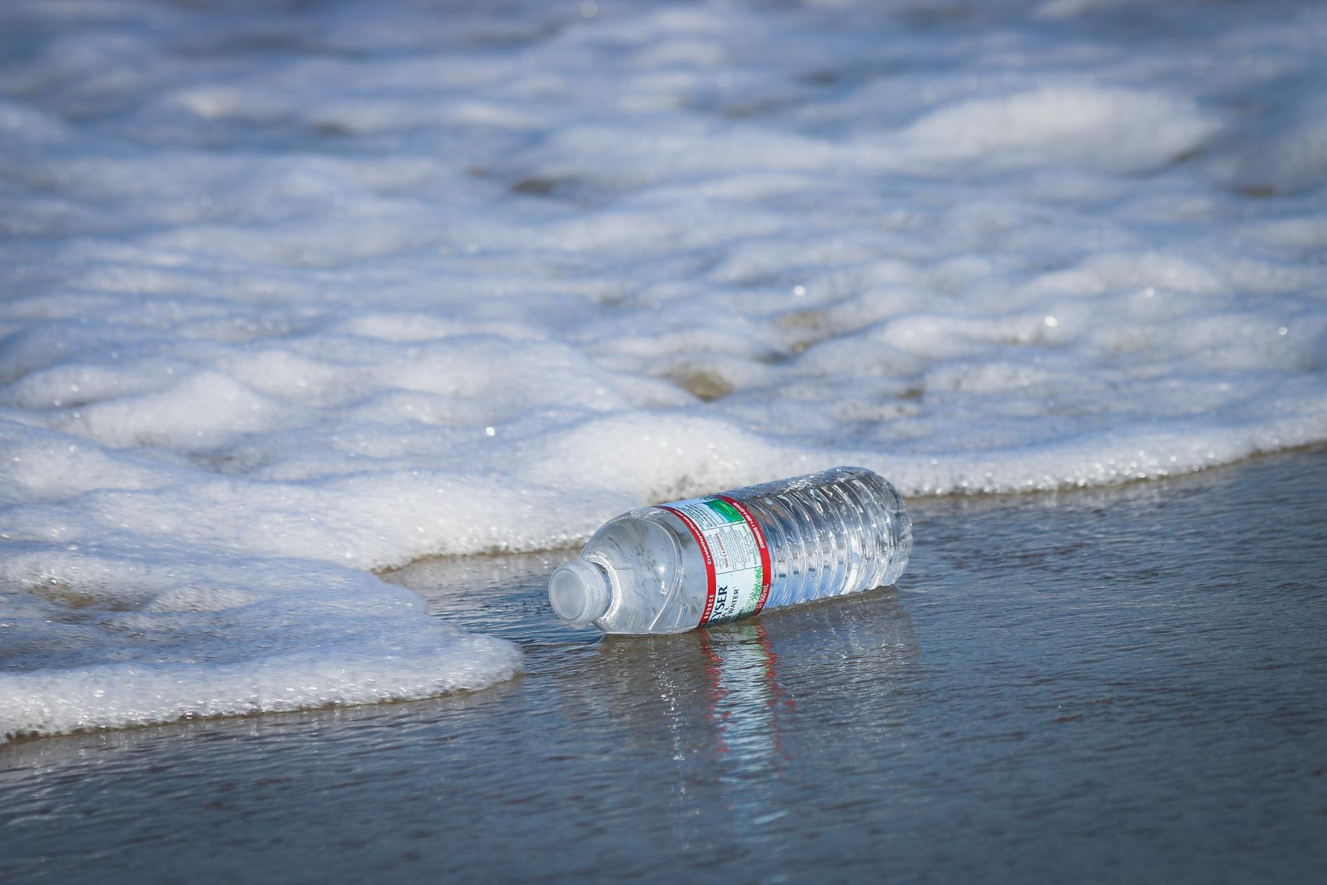 branding van de zee met plastic fles die aanspoelt