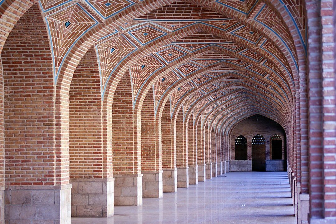 A long hallway with arches and columns in a brick building