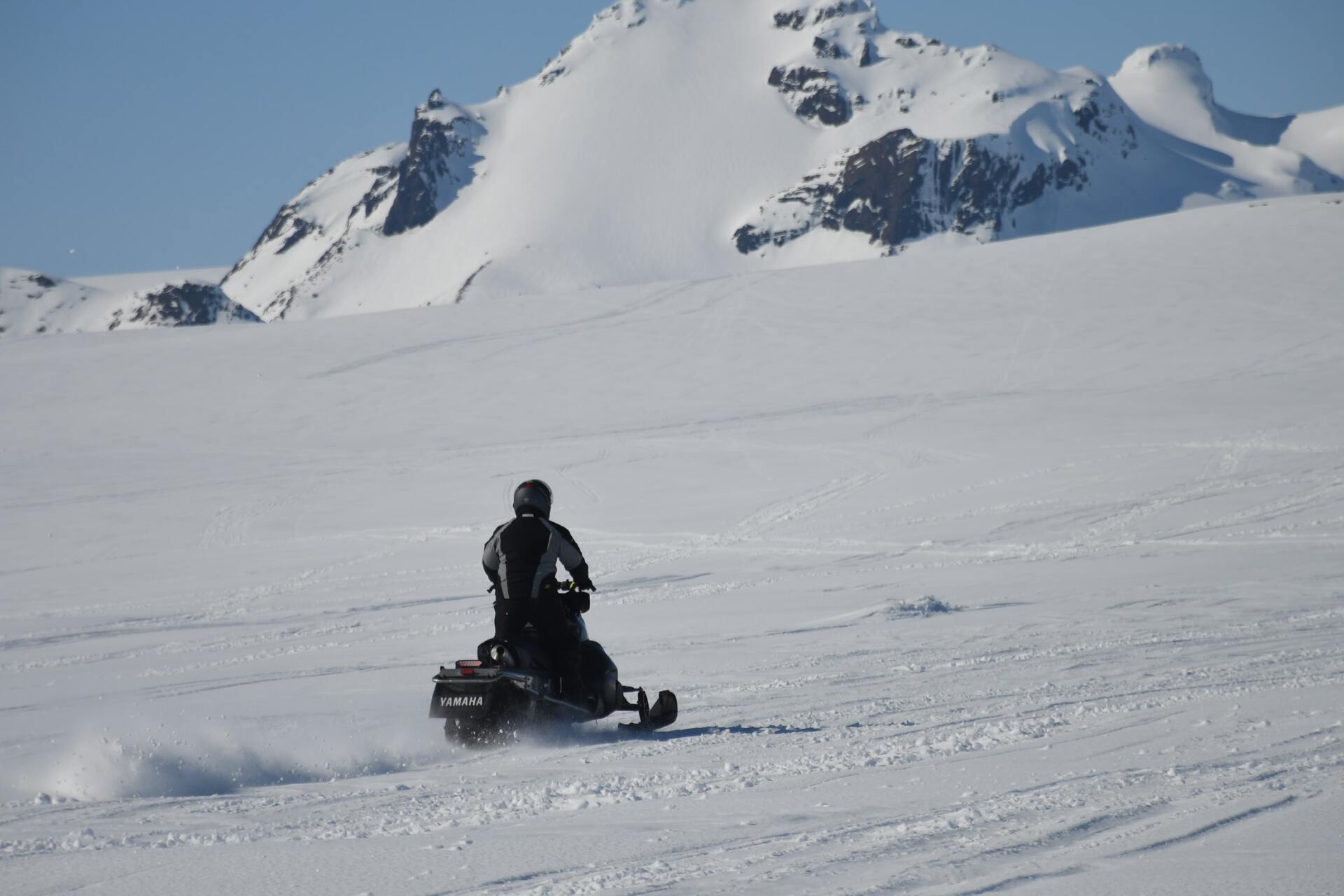 Een persoon rijdt op een sneeuwscooter op een besneeuwde berg